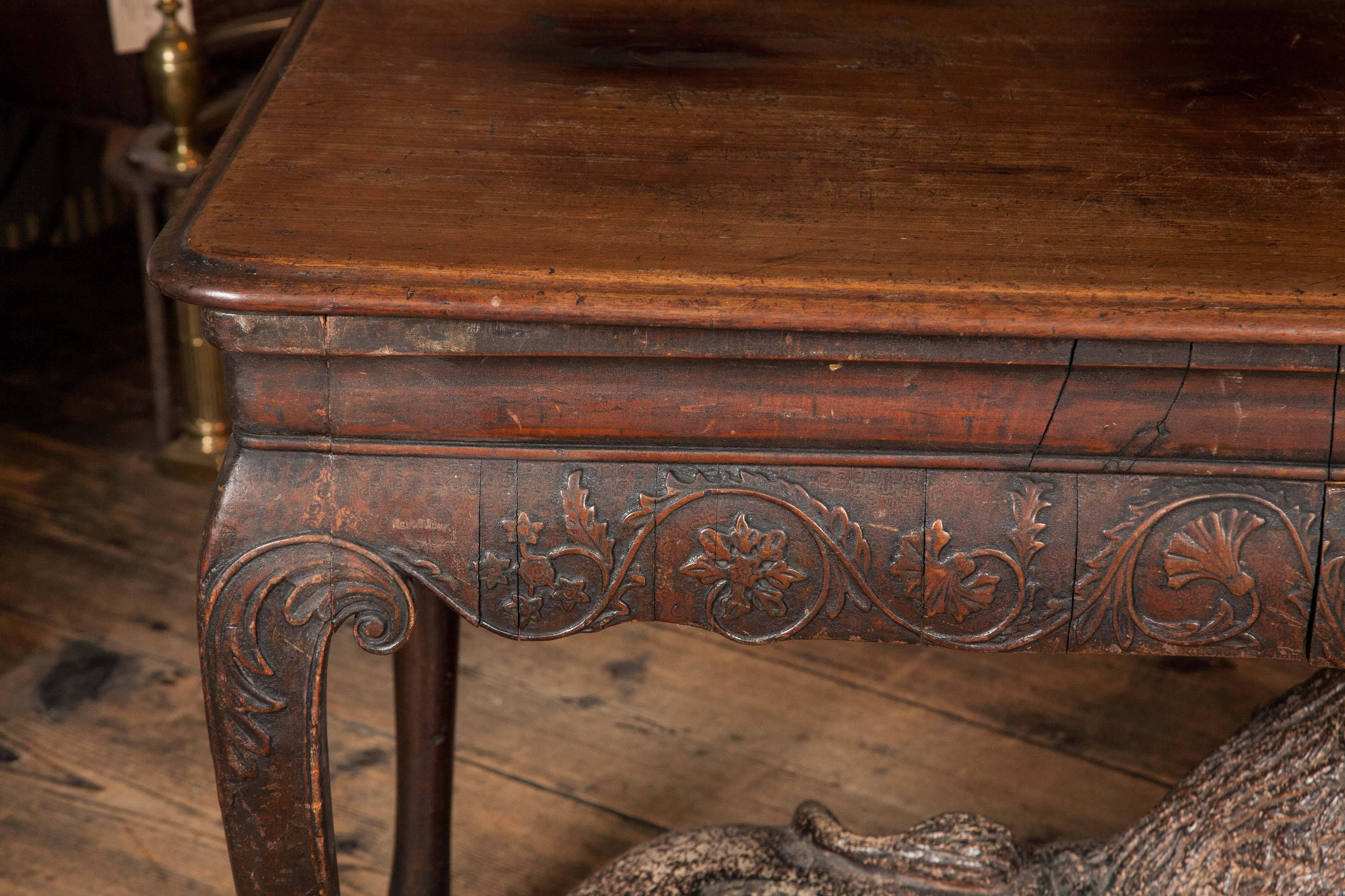 The unusual walnut top above a simple moulded frieze and an apron adorned with arabesque foliage, centred by a grotesque mask. The cabriole legs supported by paw feet. It is extremely unusual to find a table of this calibre manufactured in walnut.