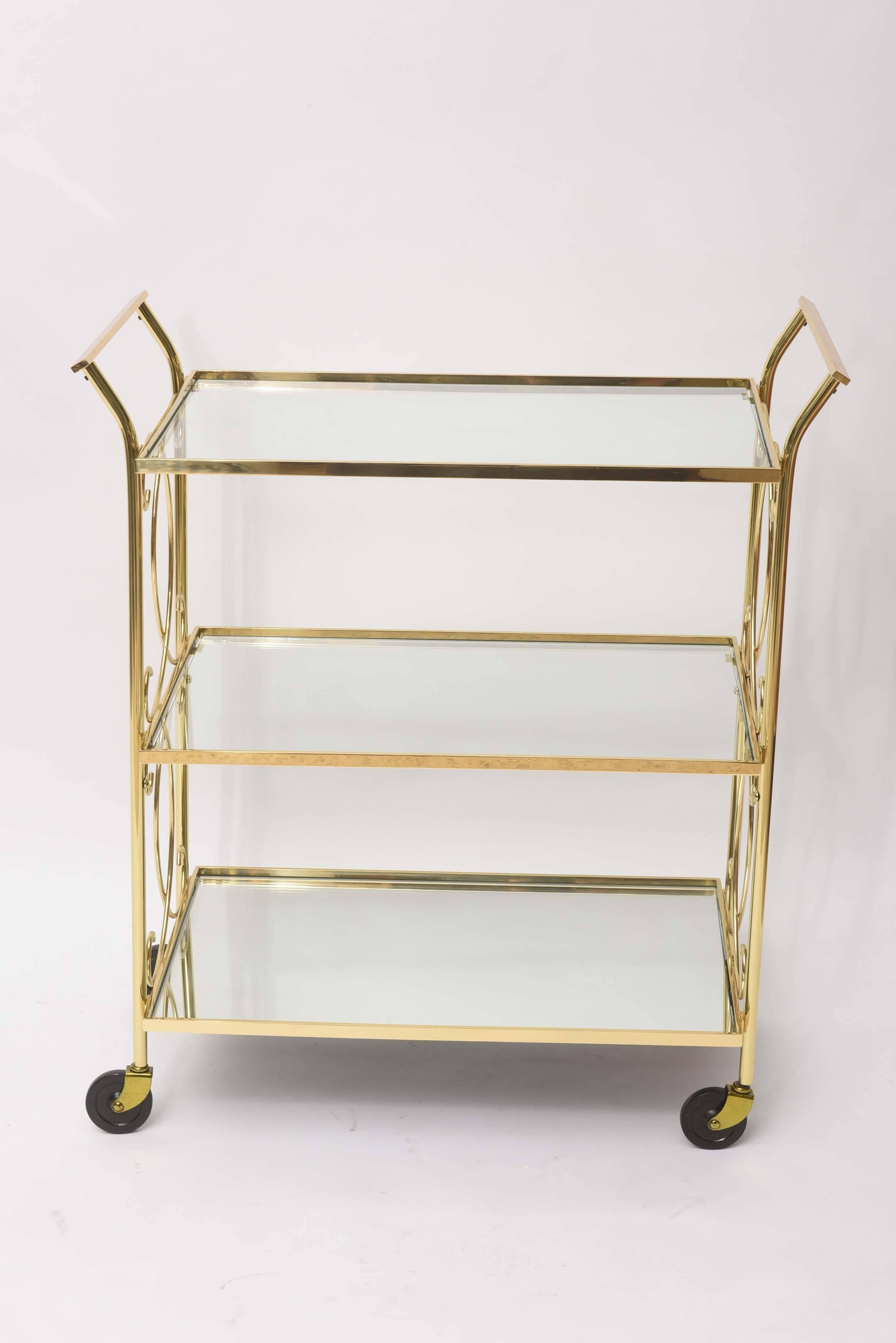 Winsome polished brass Italian drinks trolley or tea cart. This three-tiered Italian beauty has two glass shelves floating above a reflective mirrored bottom shelf. Professionally restored.