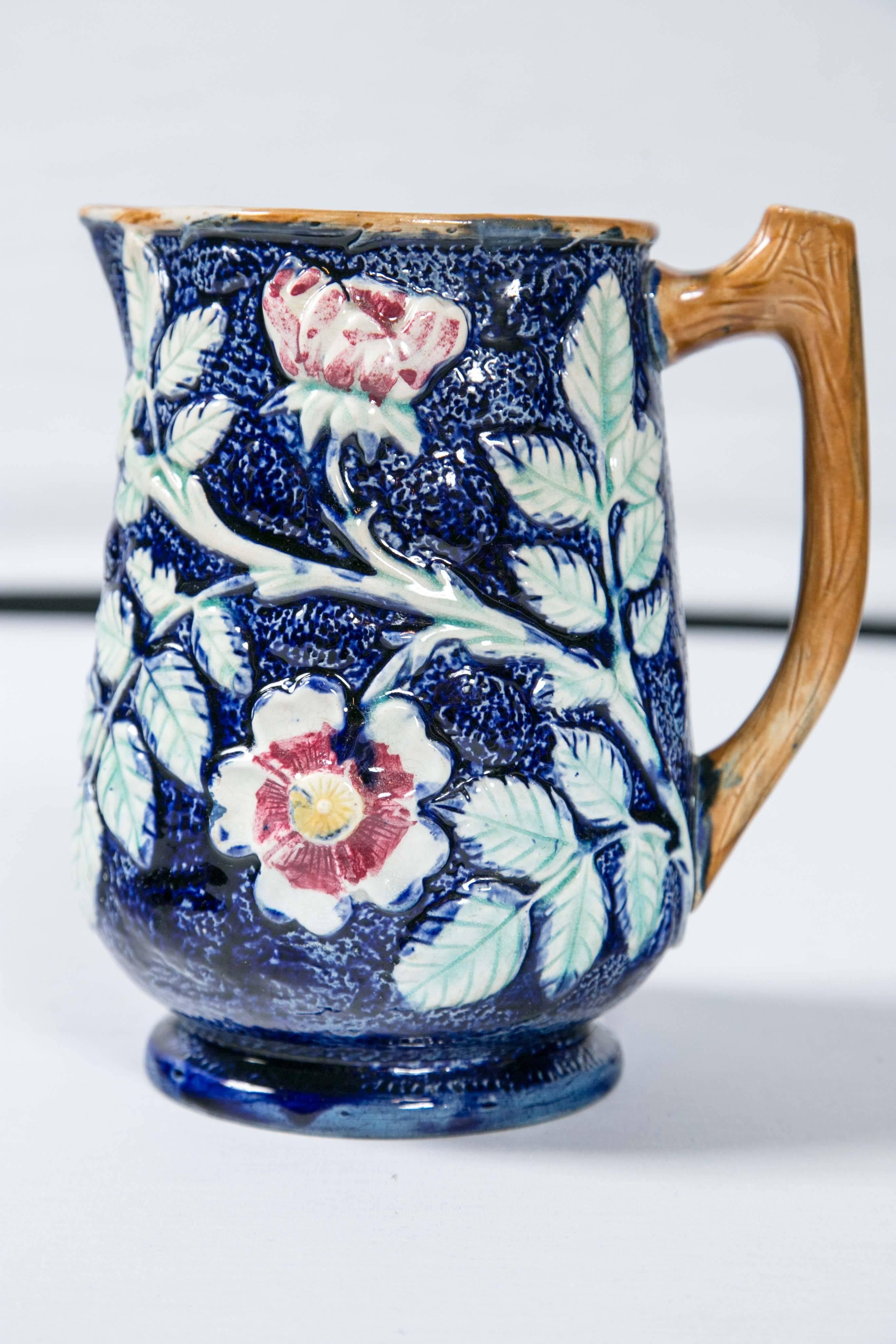 Beautiful majolica pitcher, 'Wild Rose' pattern, England, late 19th century. Cobalt blue, turquoise and pink glazes with 'branch' handle.
Overall diameter dimension: 7-1/4 inches including spout and handle.