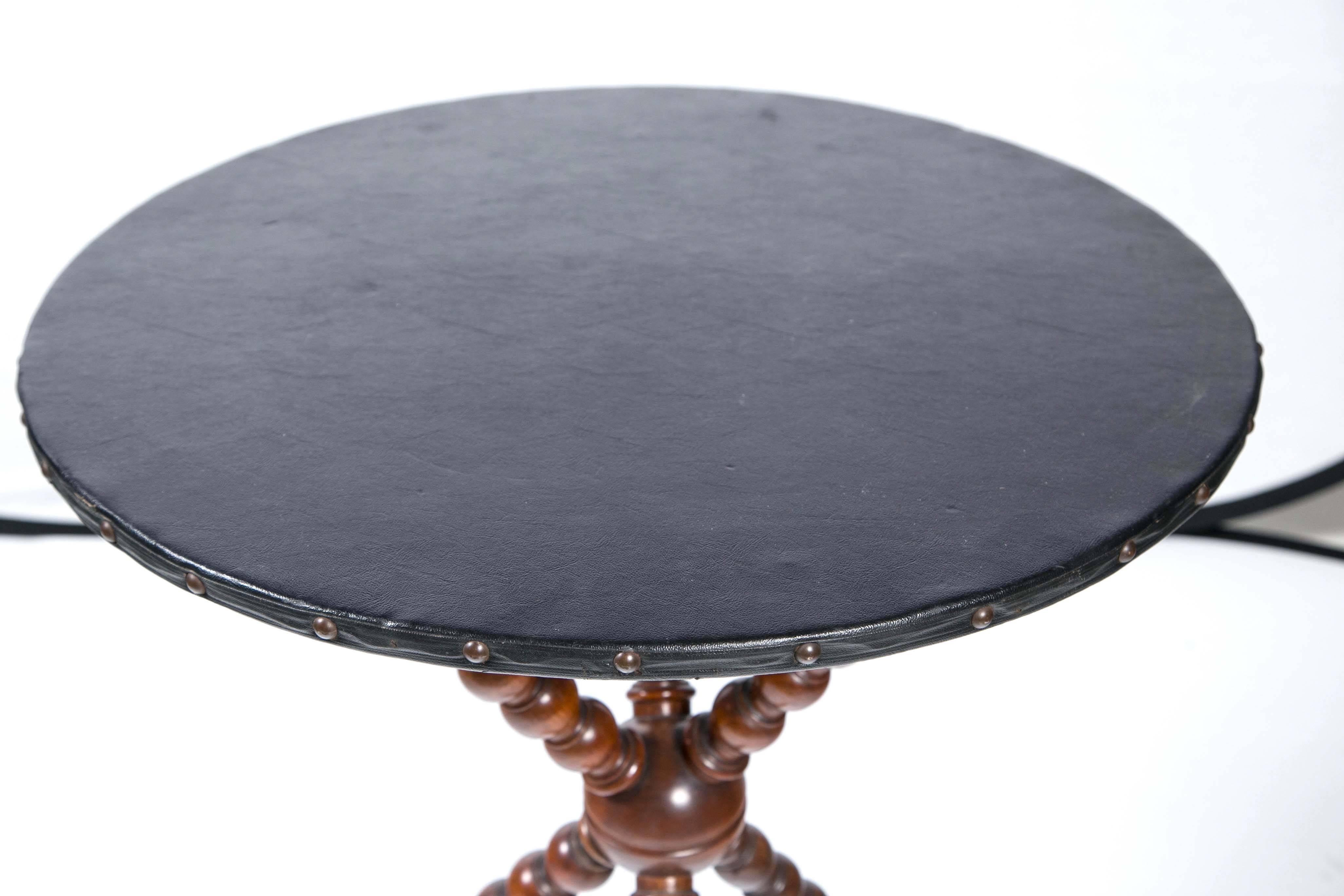 Vintage leather top table, circa 1940s-1950s. Black leather top with nail head detail. Tripod base with spindle legs.