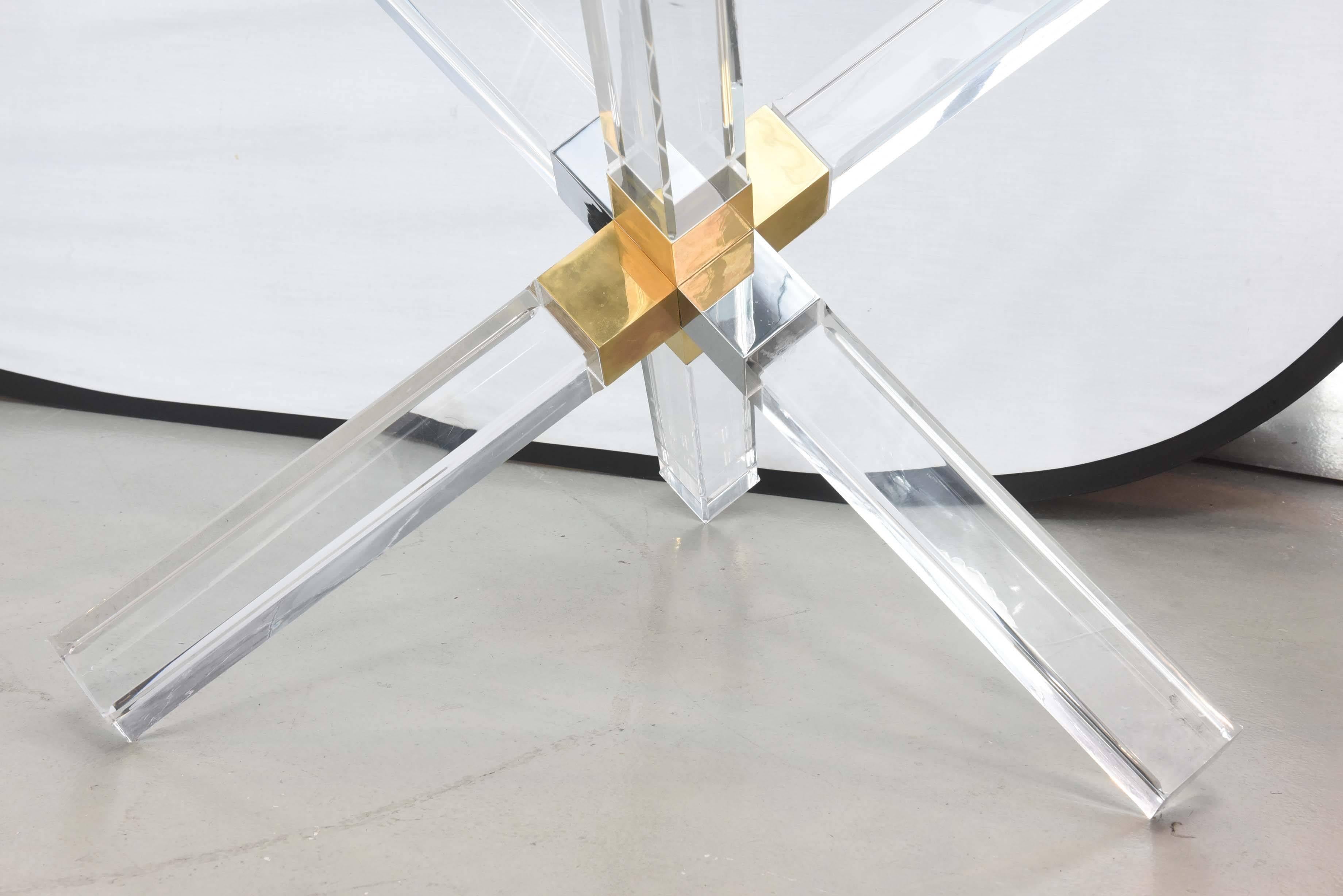 The glass top above a tripartite Lucite structure with a brass central structure.