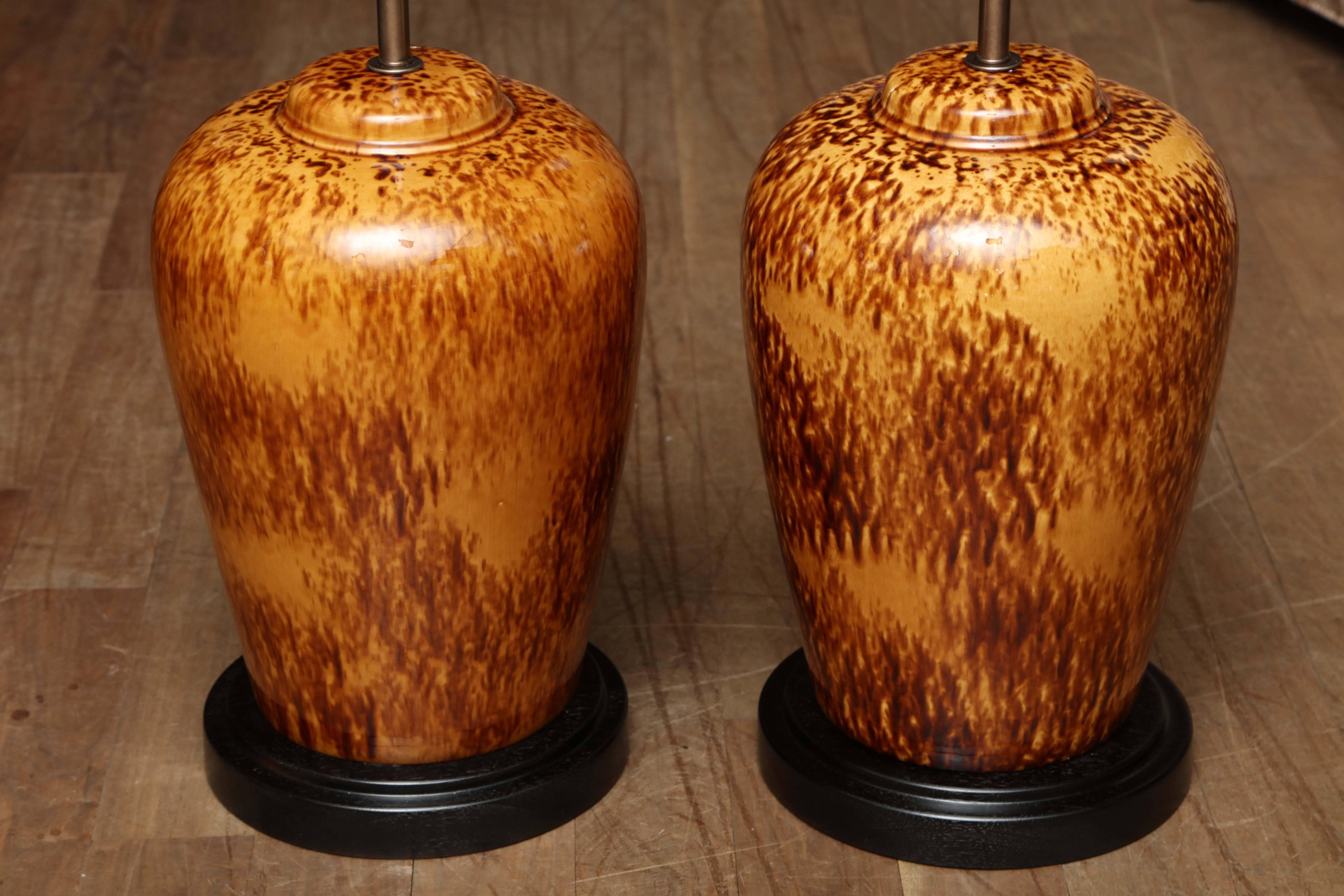 Pair of ginger jar table lamps with Rockingham style glaze circa 1940 with custom ebonized turned walnut bases.