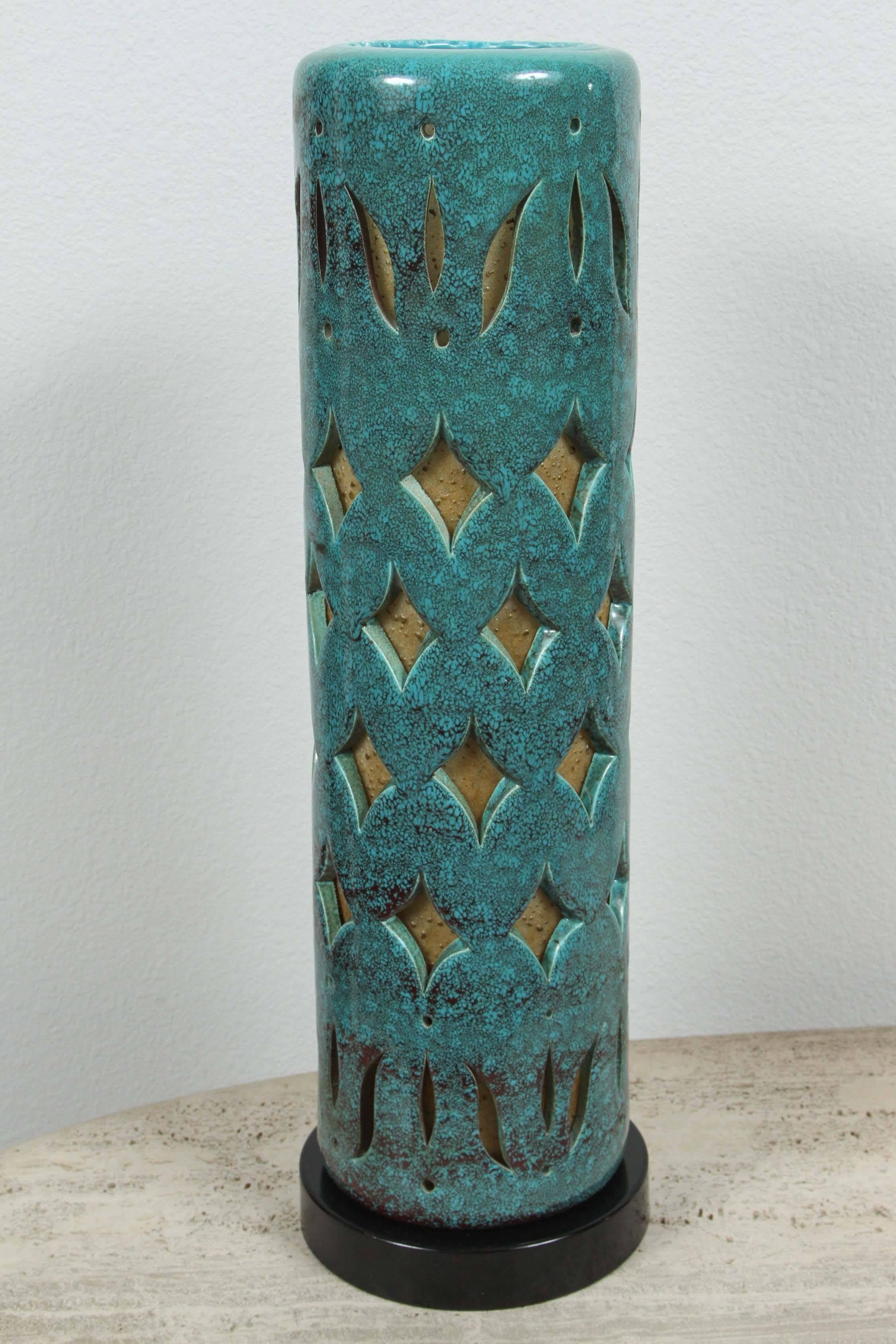 Beautiful pair of ceramic tabletop torchere lamps. 
The ceramic has a wonderful mottled teal glaze finish and has a pierced design. The ceramic is lined with a parchment paper, so when they are illuminated they have a warm glow. They have been