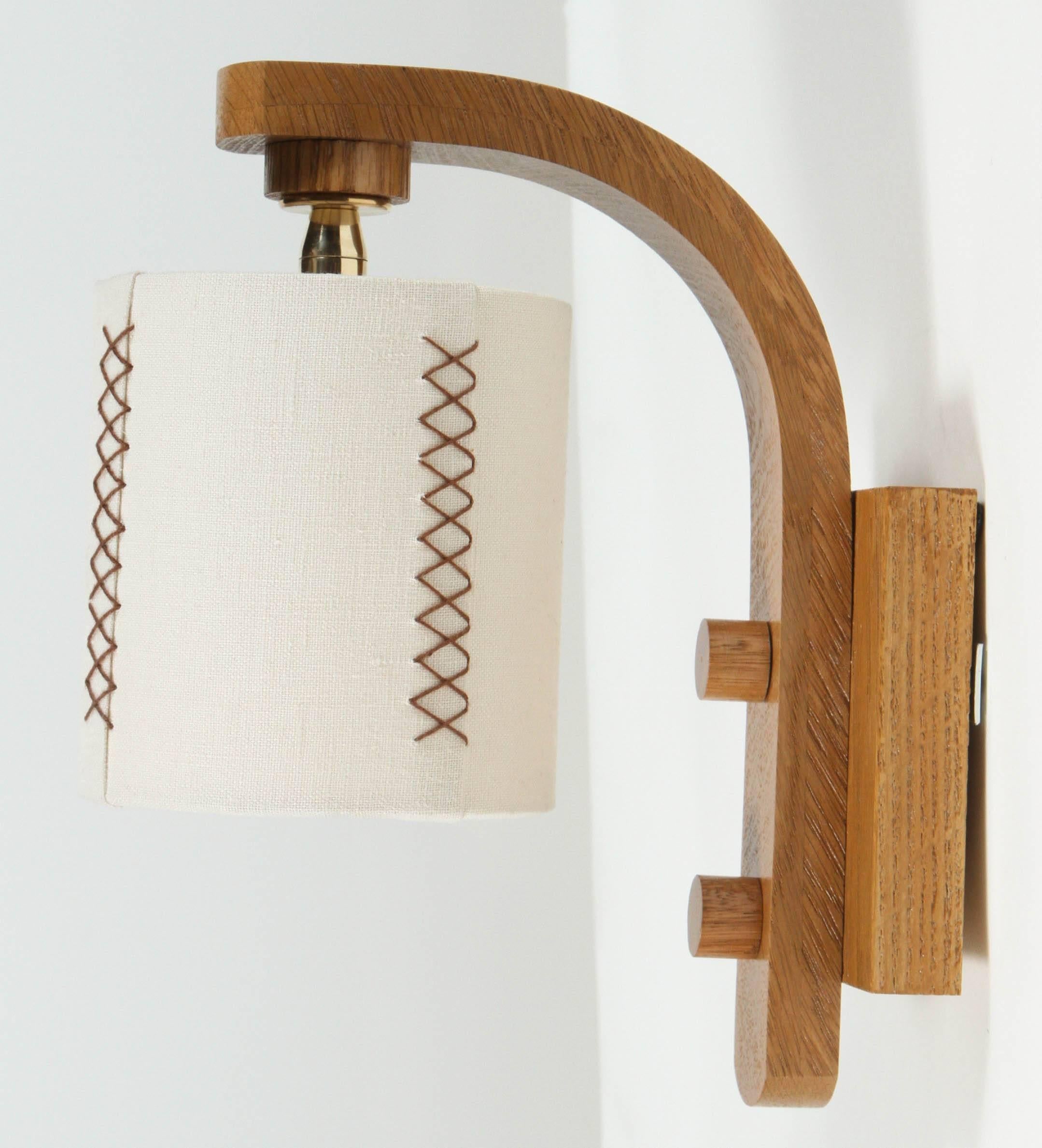 Paul Marra Oak Sconce in natural stained finish with hand-stitched linen shade. By order. 

Back plate 4in.W x 4.75in.H, diameter of shade is 4.5in.W; overall dimensions are 4.5in.W x 8.5in. projection x 10.25H.

