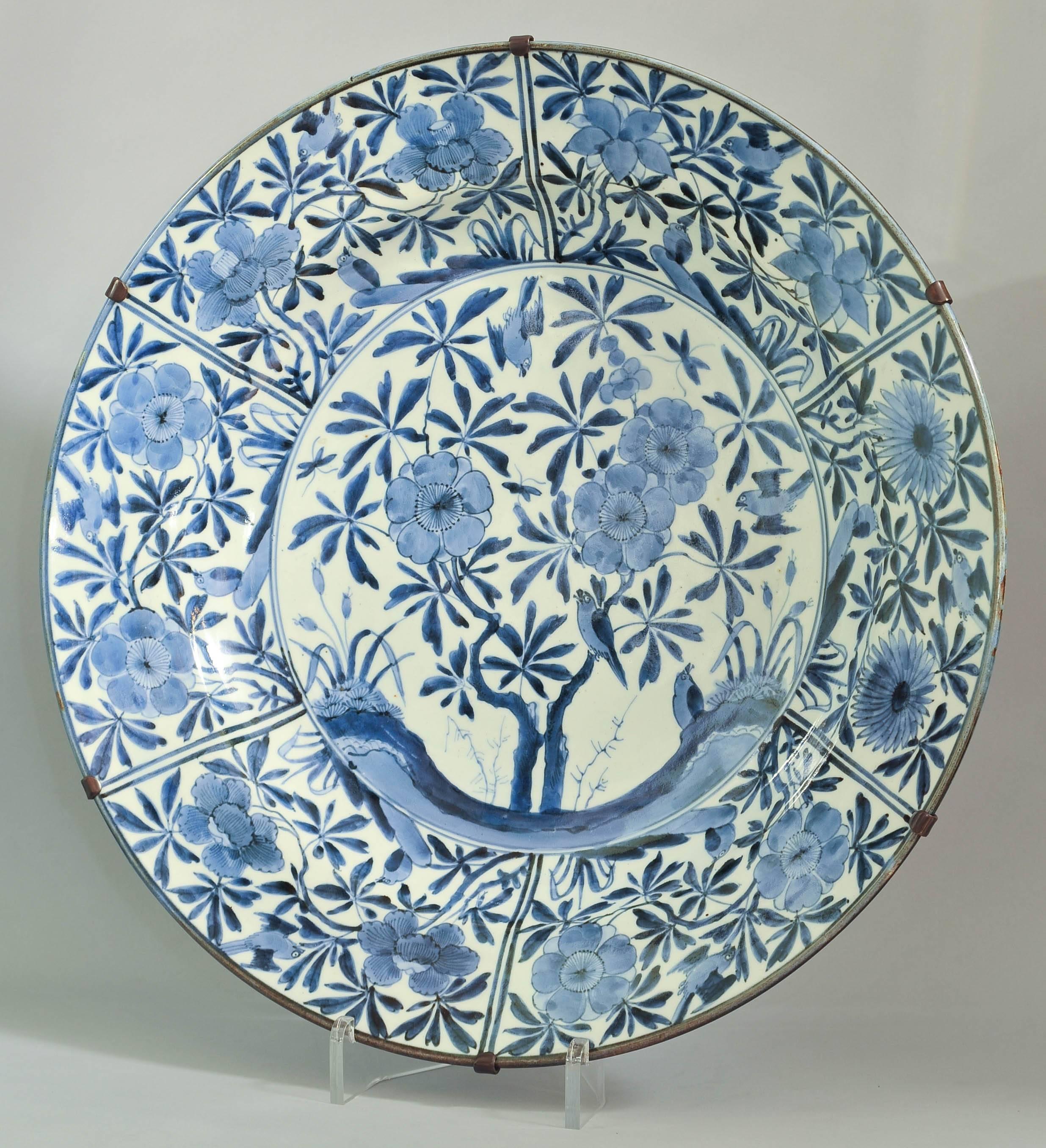 A large Japanese Arita blue and white porcelain charger dating from circa 1690 depicting birds and insects amongst scrolling blossoming tree branches and flowers. An old purpose made brass mount allows to hang in on the wall.
Perfect