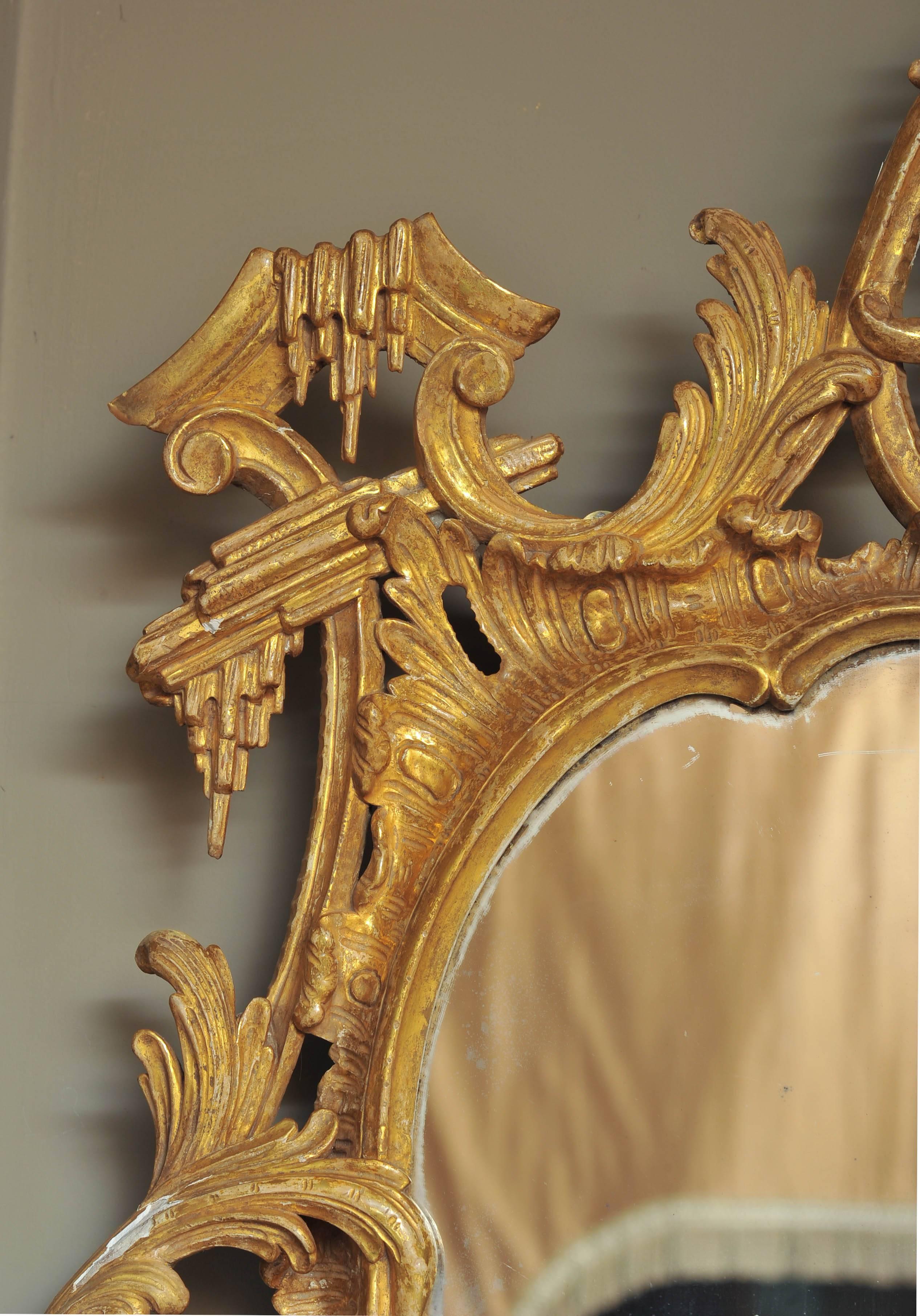 An impressively large mid-18th century carved giltwood mirror in the Rococo style.
The later shaped divided twin plate surmounted by a pierced acanthus leaf cresting flanked by icicles, the pierced 'C'@ scroll sides with trailing oak leaves and