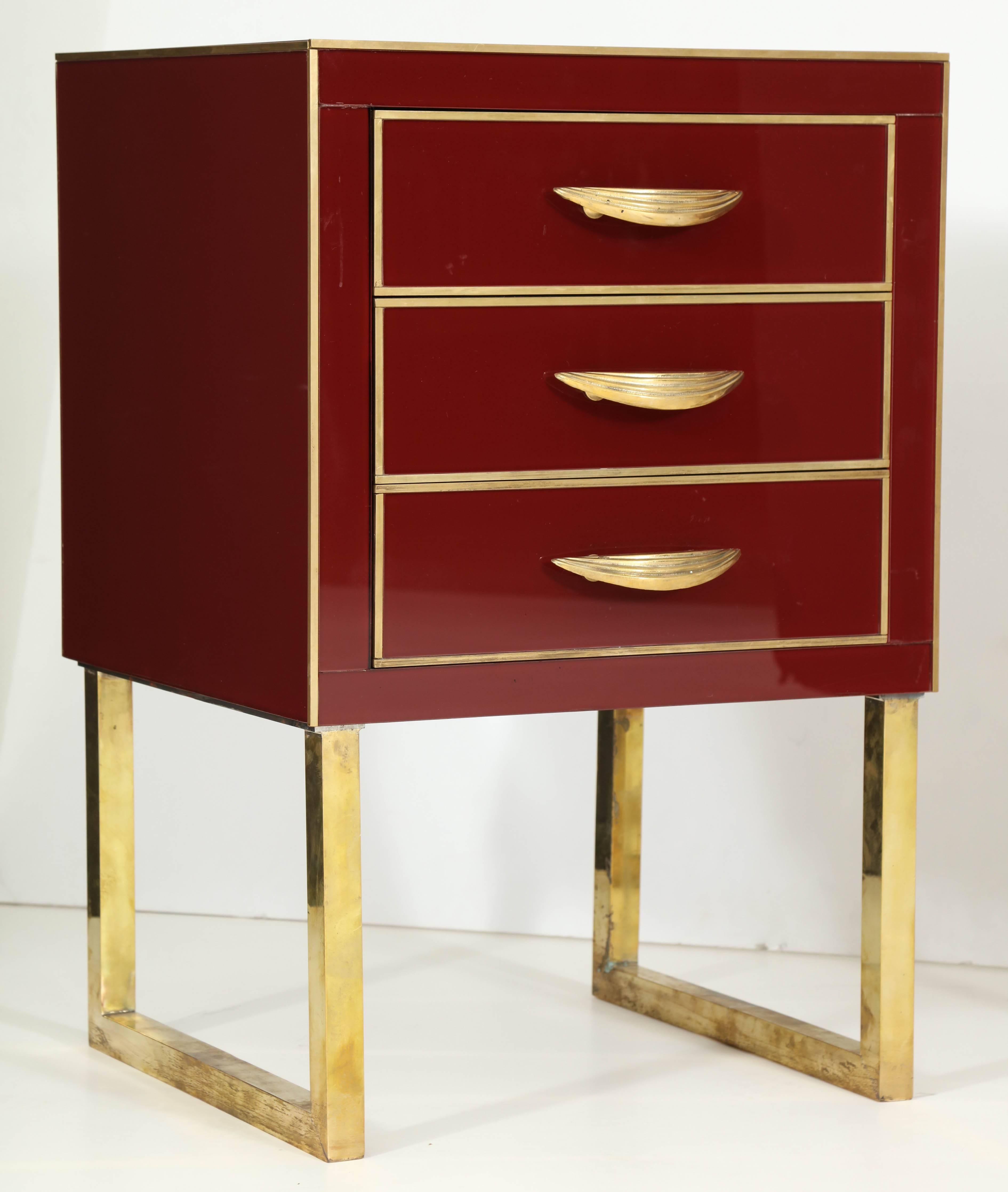 This pair of Italian Mid-Century nighstands is absolutely exquisite. Made of wood and covered in a high-gloss burgundy or deep red colored Venetian opaline glass with beautiful polished brass inlays, pulls and brass flat legs. 

These nightstands