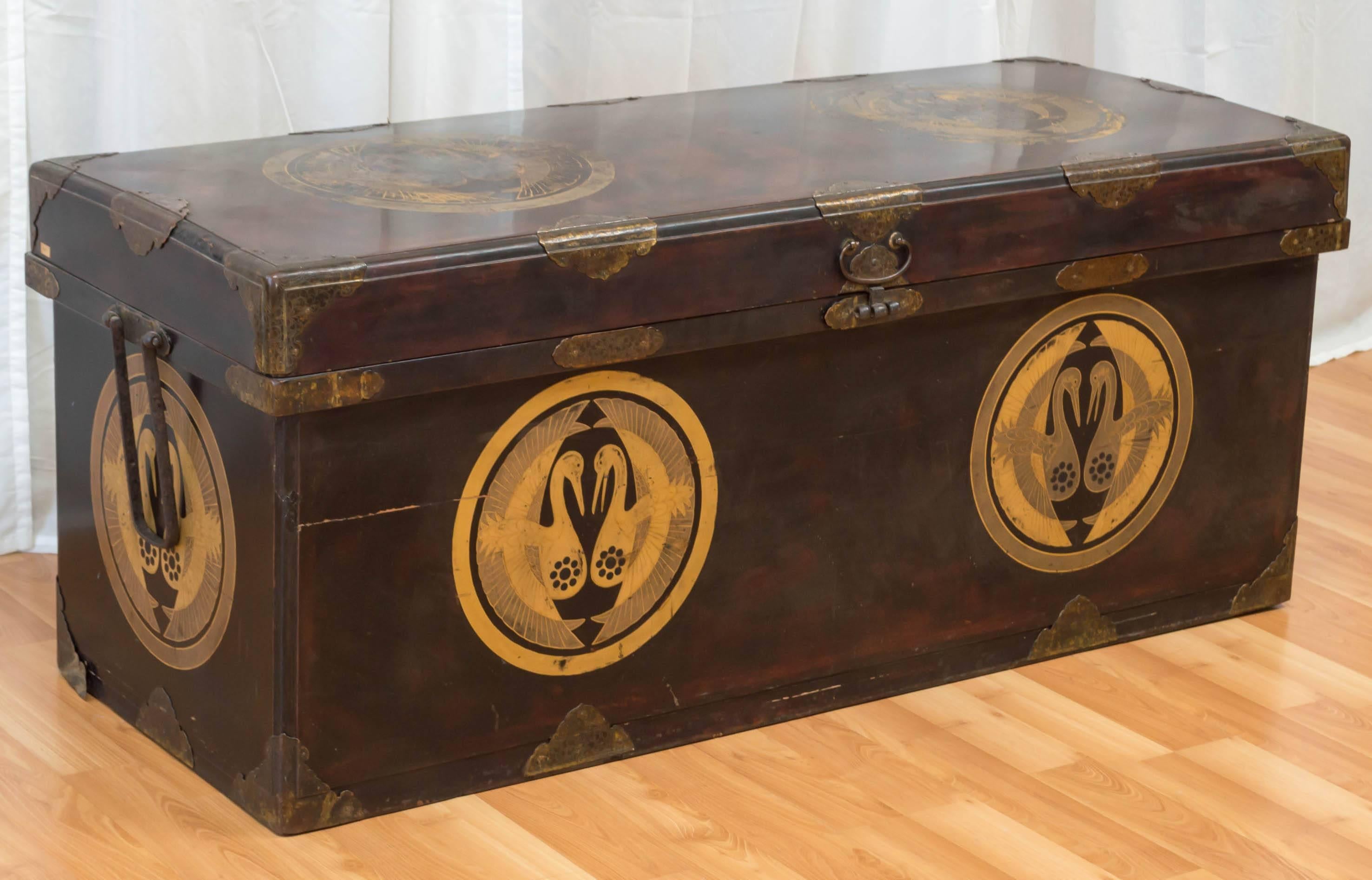 A very large wood Japanese wedding or storage chest or trunk, late-Meiji or early-Taishō period. Embellished with a beautiful gold kamon motif, brass accents, and rice paper lining.

Chest is constructed of a rich mahogany-like wood, and has a