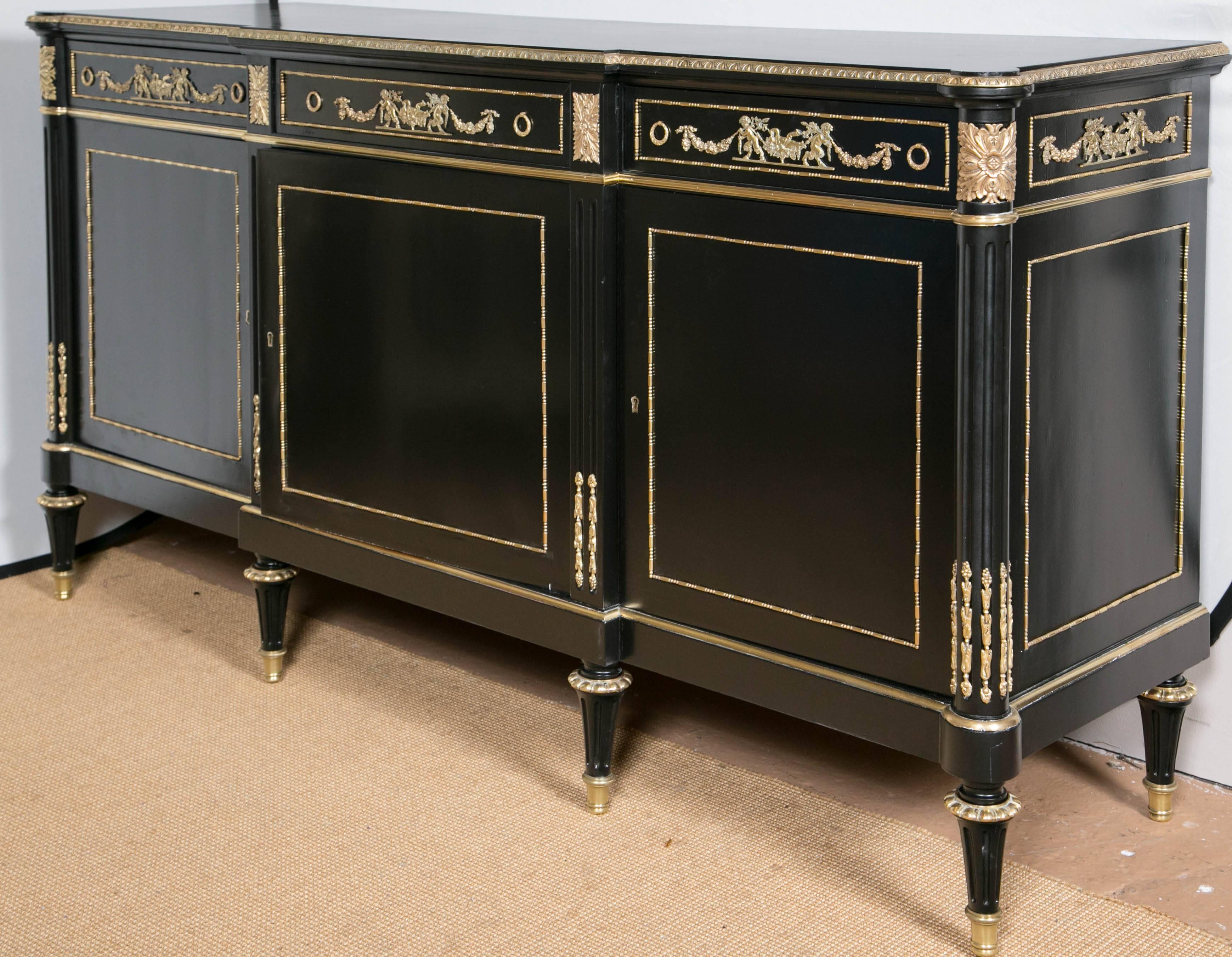 Louis XVI style sideboard by Maison Jansen. A spectacular bronze-mounted cabinet by Maison Jansen. The bronze sabots on tapering legs terminating in bronze caps supporting a finely chiseled bronze-mounted cabinet. The center having three large doors