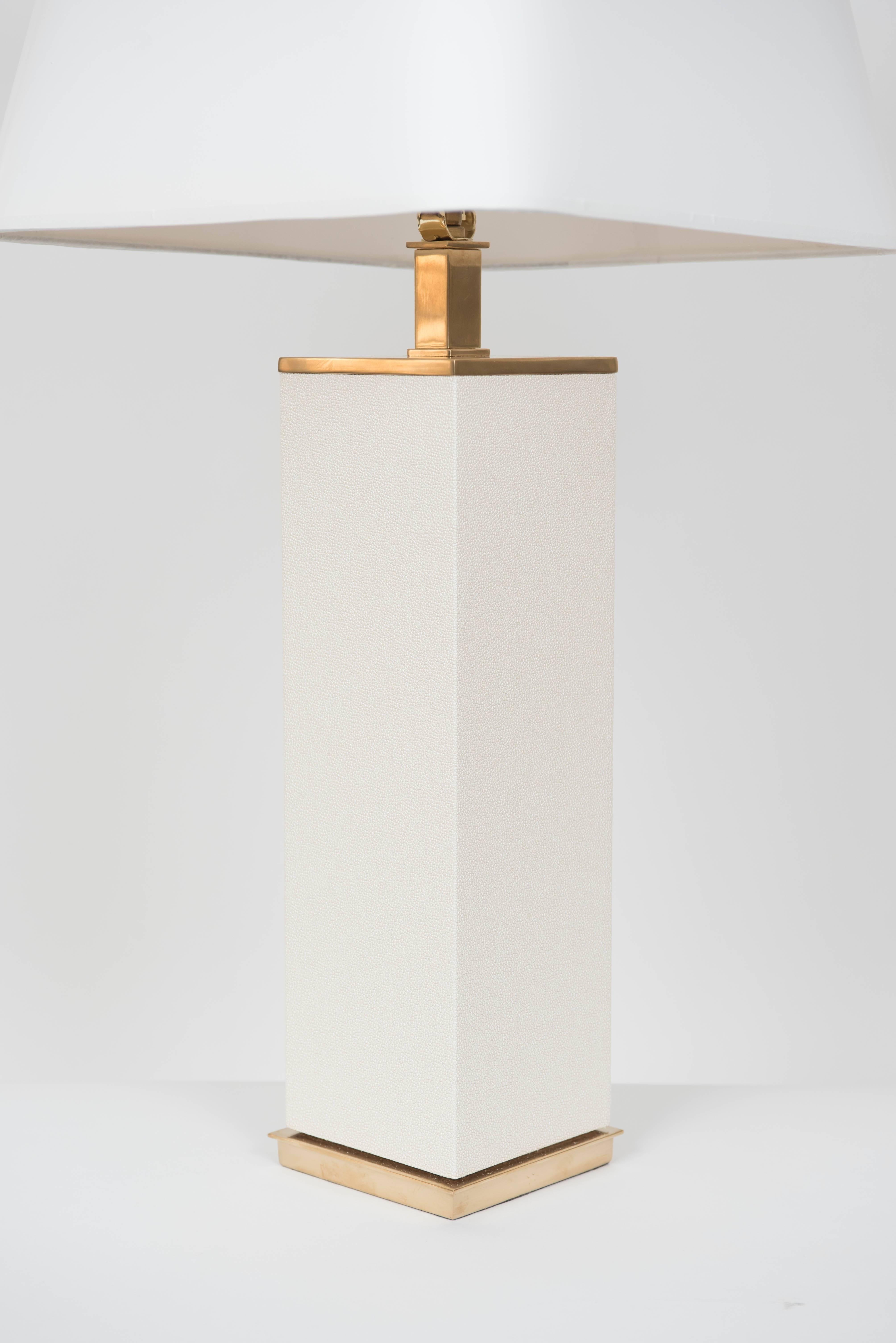 The pair of modern lamps are wrapped in a warm white faux shagreen and accented with patinated brass base and matching finial. New shades have been
designed for the lamps and are optional. With shade the overall height of the lamp 30
