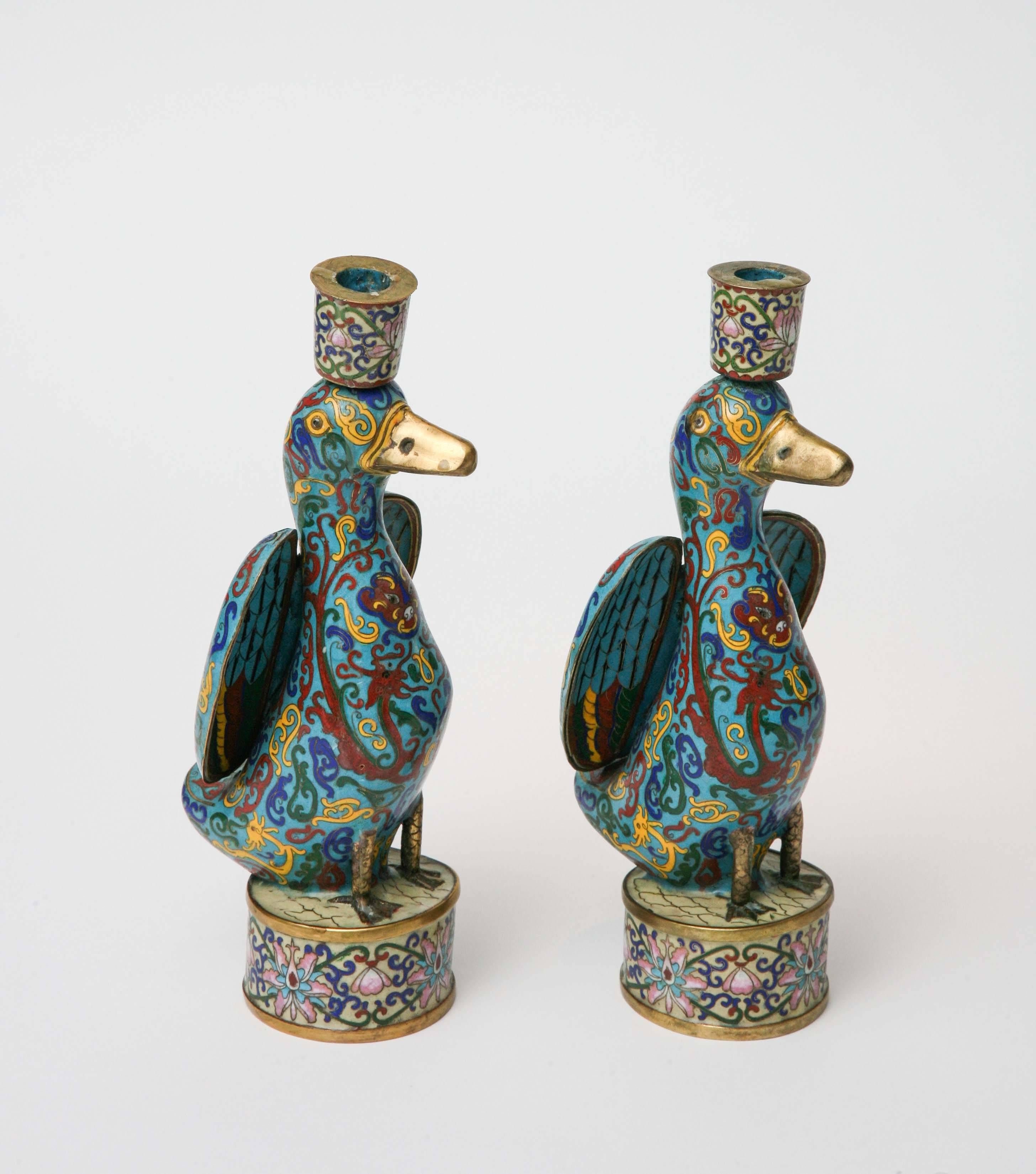 Whimsical pair of duck cloisonné candleholders made for the Chinese export market. The pair shows remarkable craftsmanship and has vibrant colors of turquoise and deep blue, pink, yellow, and crimson. 

The technique of containing enamel within
