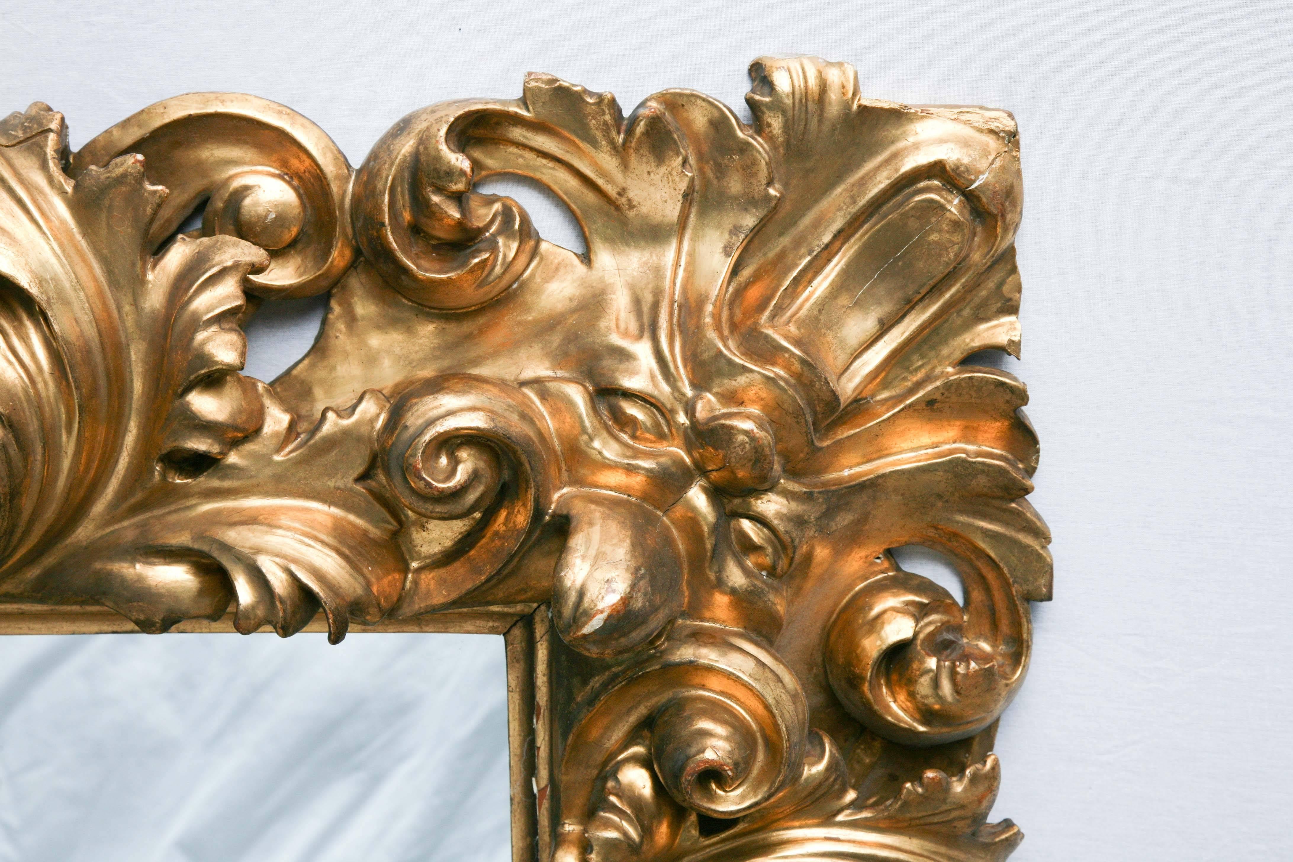 This robust giltwood from Italy is deeply carved with intricate undercuts. The corners are grotesque masques which flow directly from the foliate forms. Mannerist mirrors such as this were very popular in 18th century Italy because they reflect the