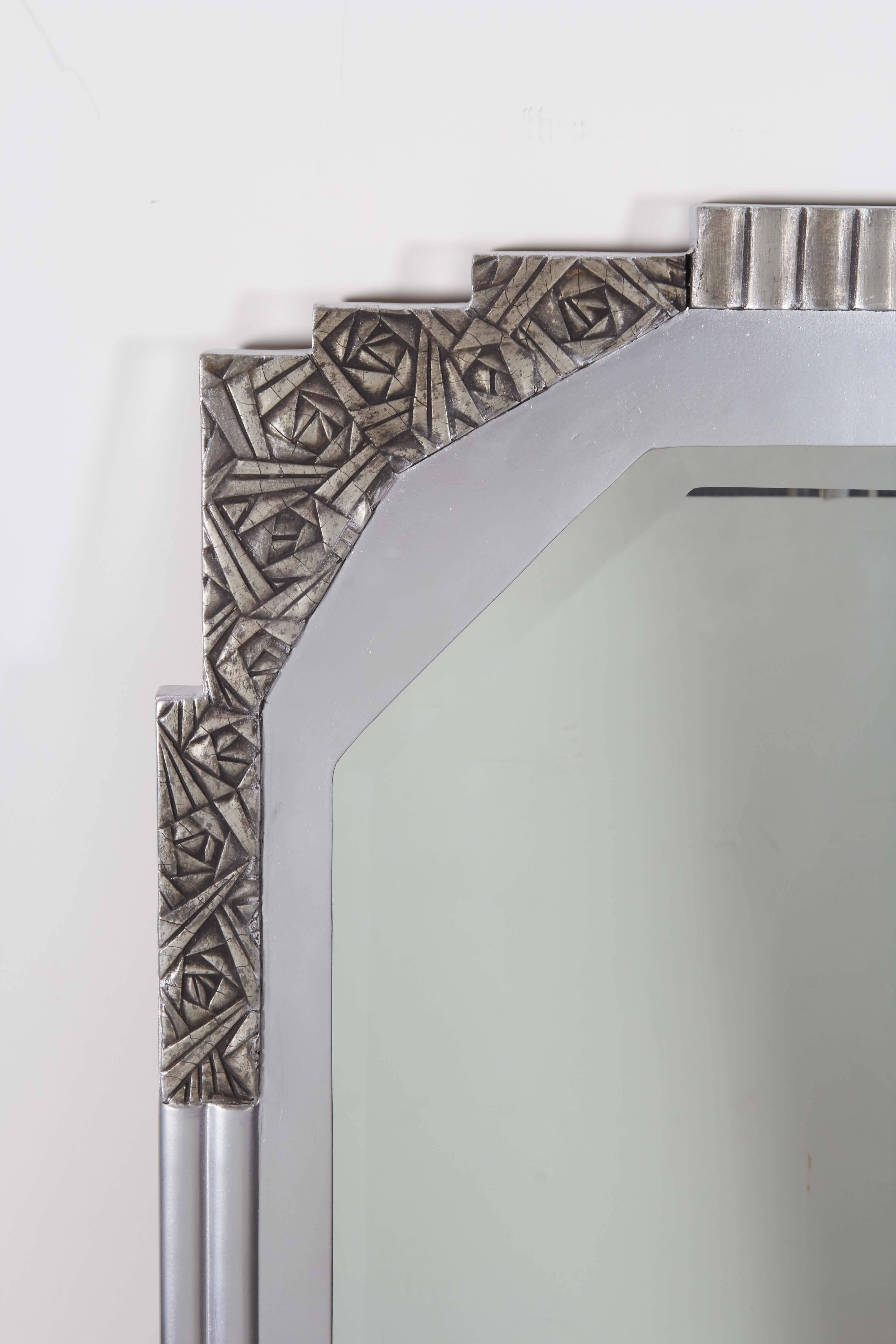 A tall rectangular, original French Art Deco silvered wall mirror with fluted sides. 
The top surround features a highly stylized rose and angular detail that
flanks the cut cornered beveled mirror inset. 