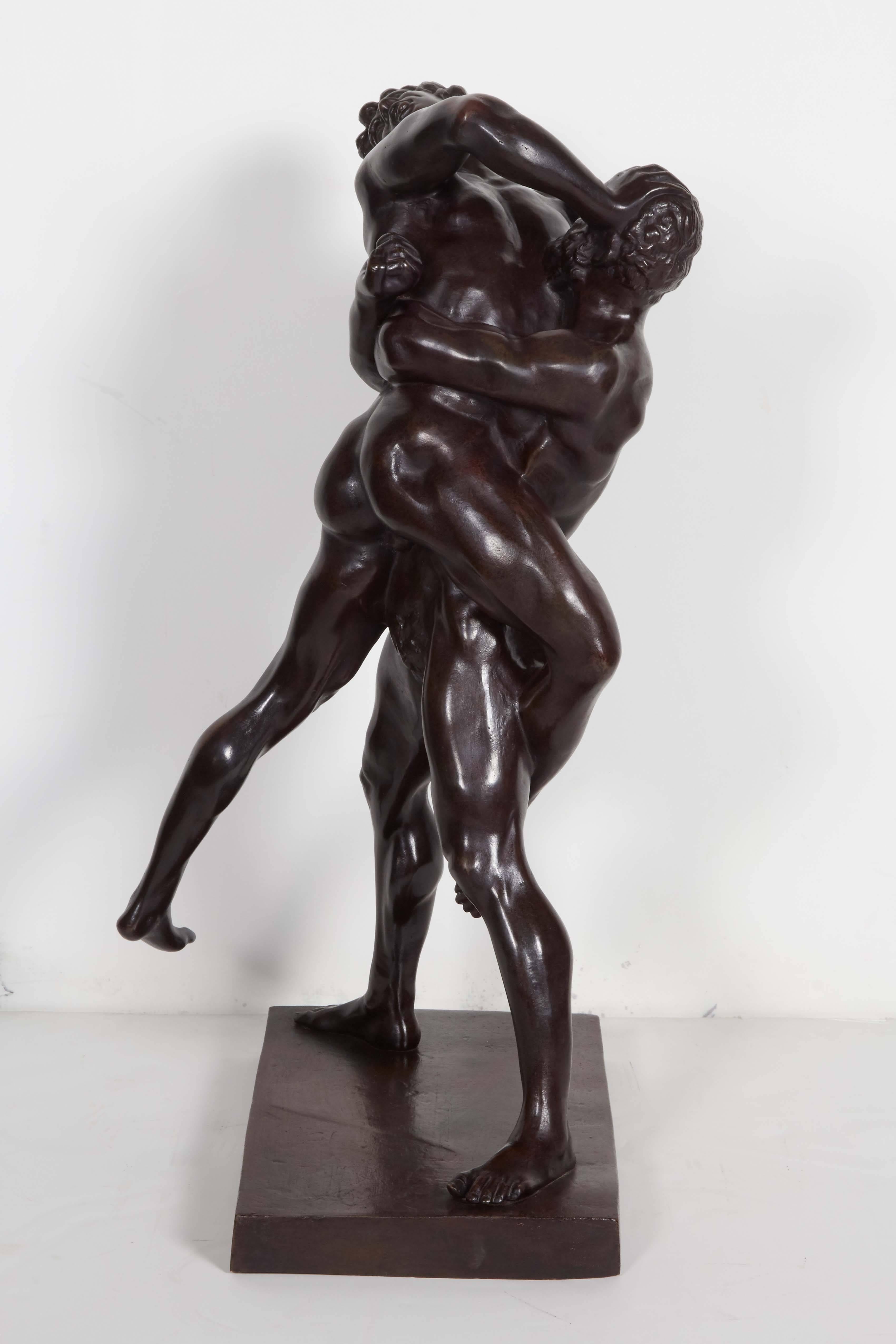 Powerful action packed statue of two muscular, nude male athletes, finished in a deep chocolate brown patina. Kinetic movement and anatomical detail make this a robust and compelling sculpture. 
After the Greek wrestlers in the National Museum in