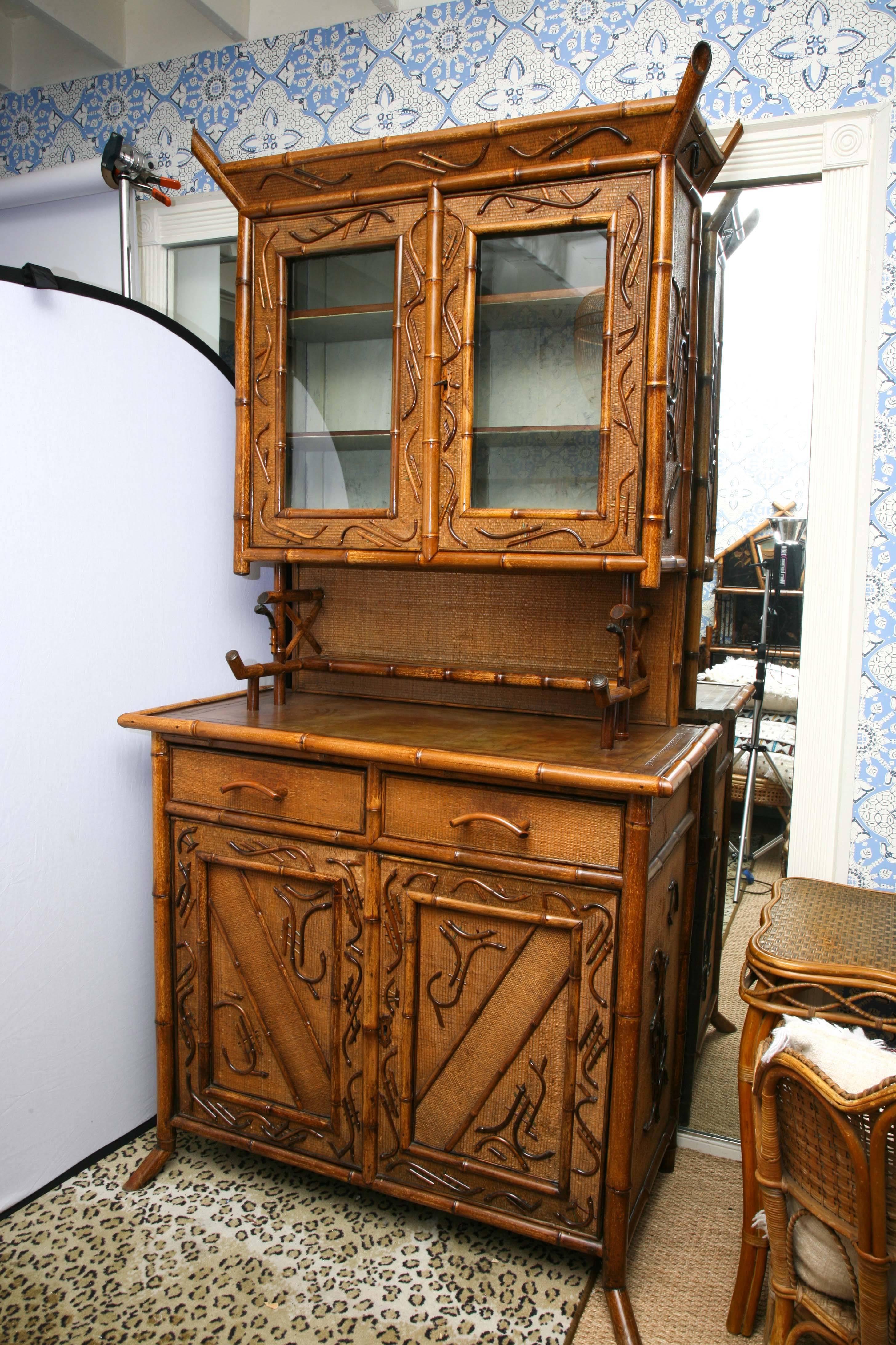 19th English two-part bamboo cupboard, the upper cabinet with glass fronted storage, over a two-drawer, two-door base cabinet with tooled leather top, the door panels with applied bamboo and rattan decoration, Measures: 92" H x 47" W x