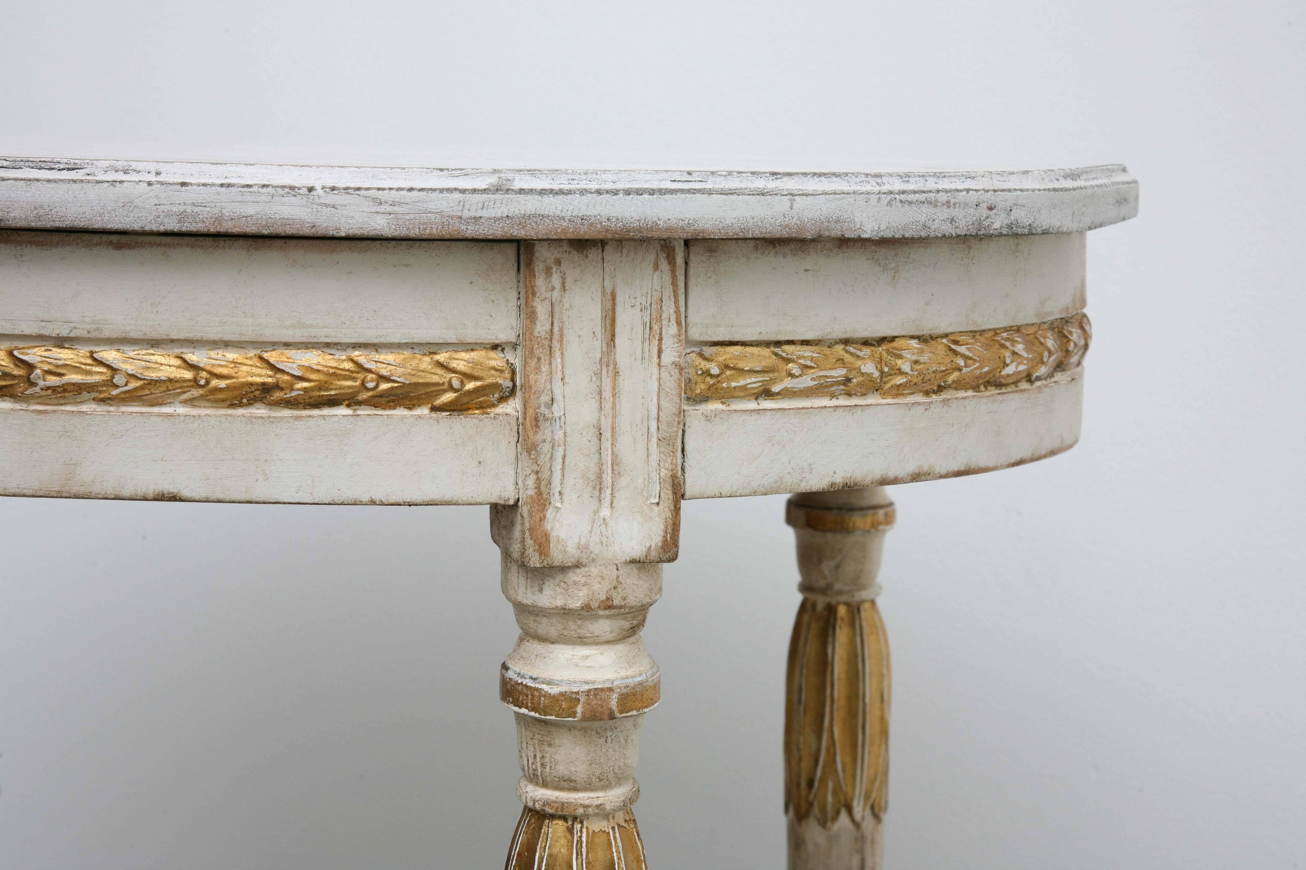 An antique Swedish 19th century Gustavian oval table, painted and giltwood
with subtle faux marble top, lovely gold leaf Acanthus leaf border around apron, carved and fluted tapered legs, joined with bottom stretcher with carved urn. Swedish cream