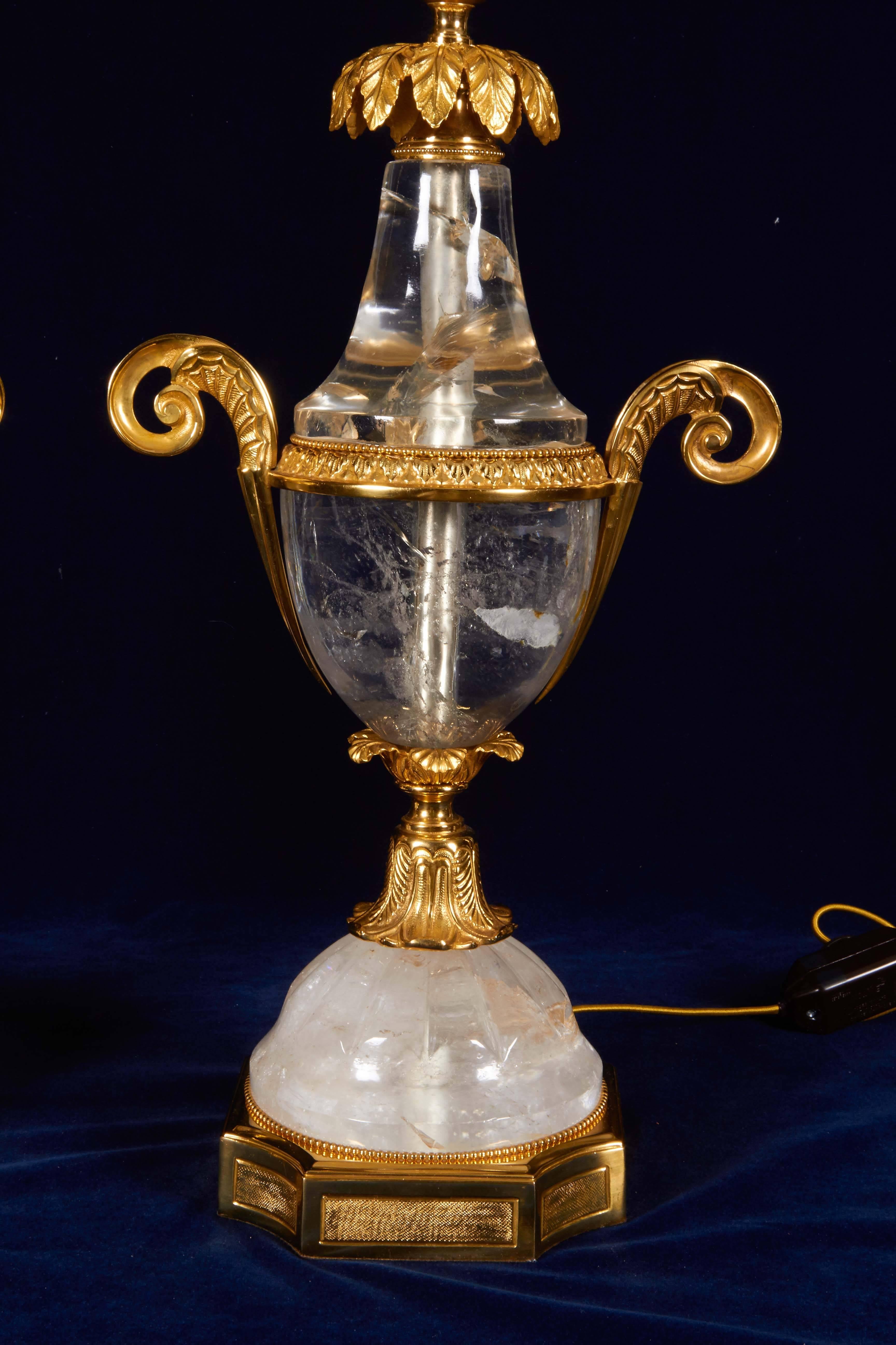 Pair of French Art Deco style hand-carved and engraved rock crystal and dore bronze lamps, attributed to Maison Baguès.
Of shield shape, flanked by broad scroll handles and surmounted by a foliate bobeche, on a canted gilt bronze square base, late