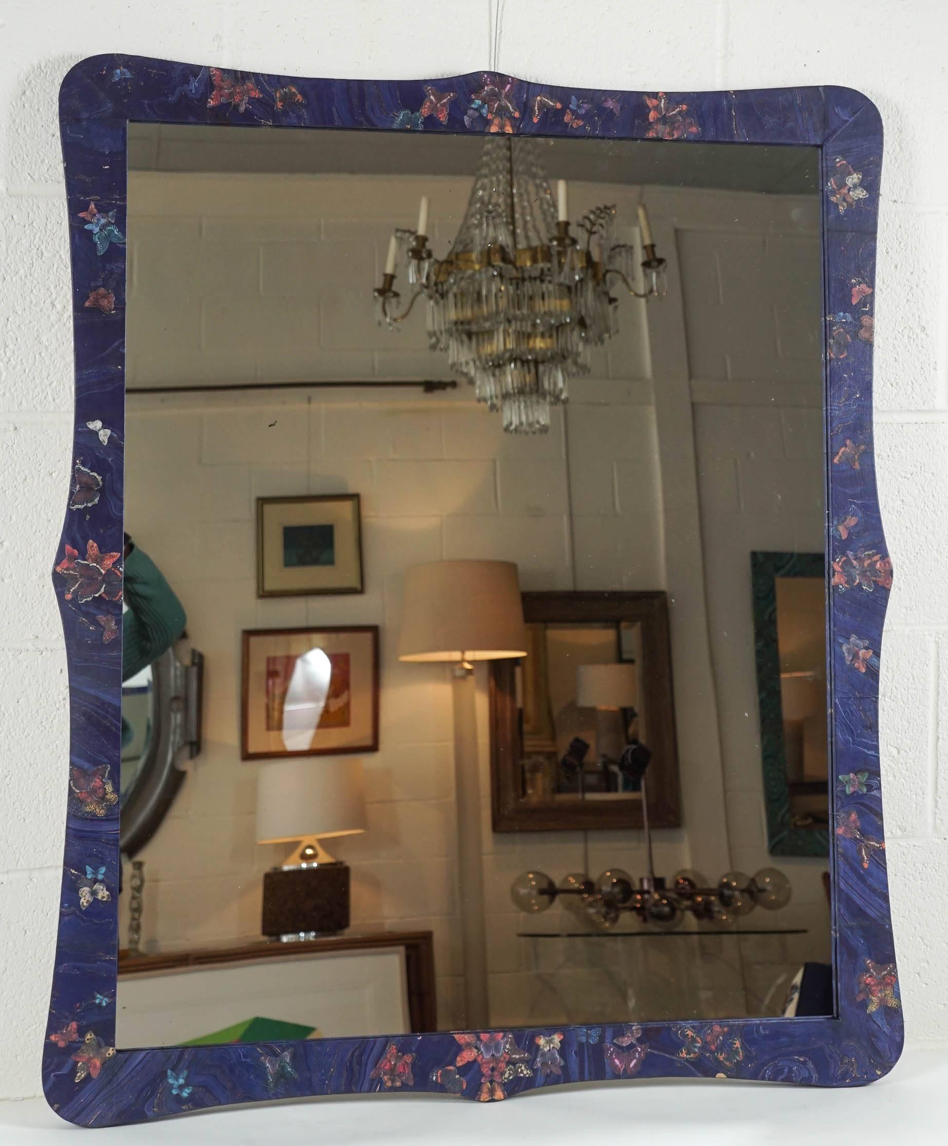 Here is a beautiful mirror decoupaged with a cobalt blue marbleized paper with gold striations and cut-out butterflies. The butterflies flutter across the surface and have abstracted Formations throughout.