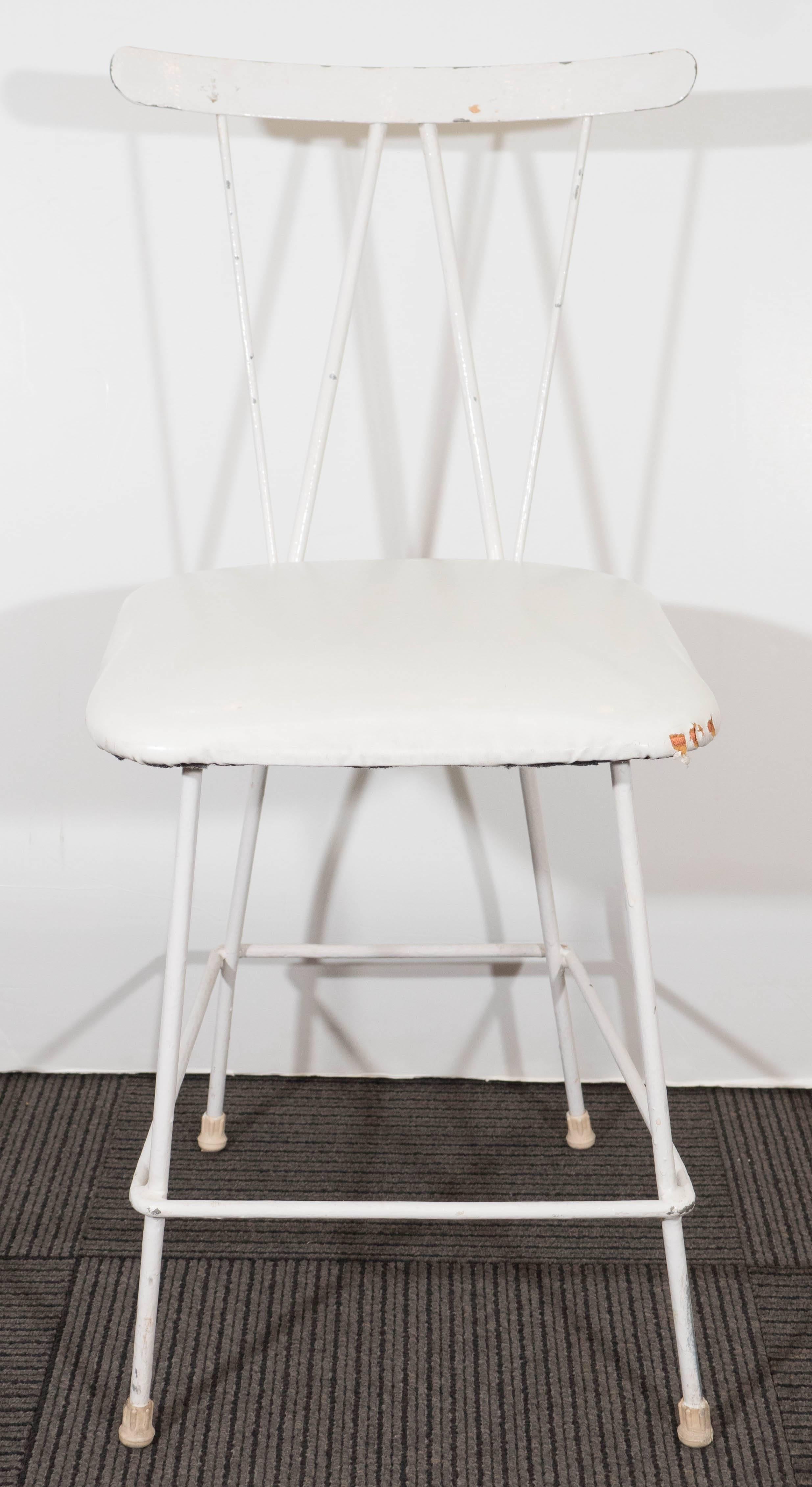 A 1950s highly linear side chair by designer John B. Salterini, with cushioned seat against a white enameled iron frame and square stretcher, on capped feet. Despite age appropriate wear, including presence of chips and scuffing to enamel finish, as
