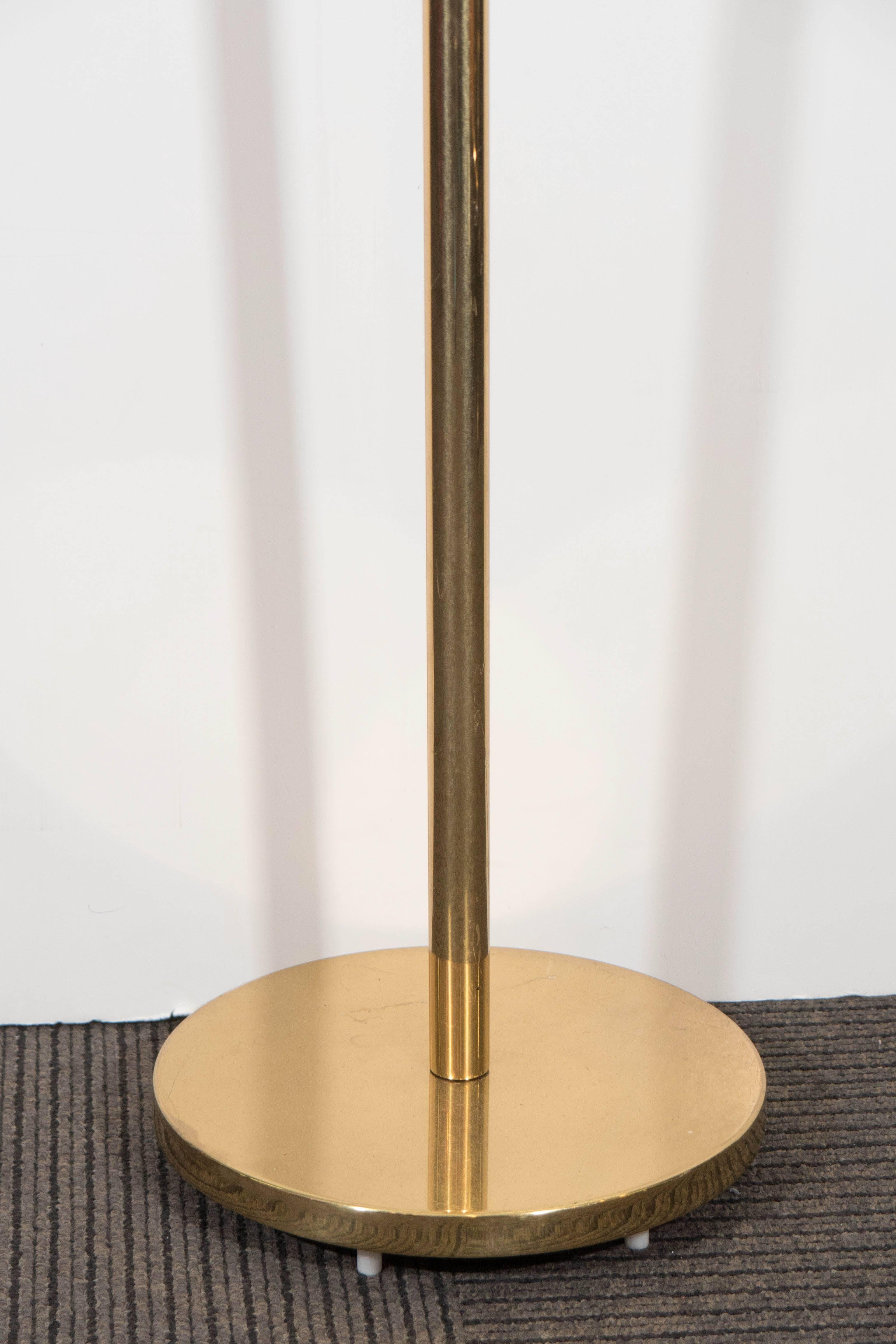 A vintage brass floor lamp, produced by Casella, circa 1970s, with Empire shade in white linen, surrounding ceramic double s sockets, on lengthy stem and raised circular base. Overall good condition, with minor presence of scratches to brass and