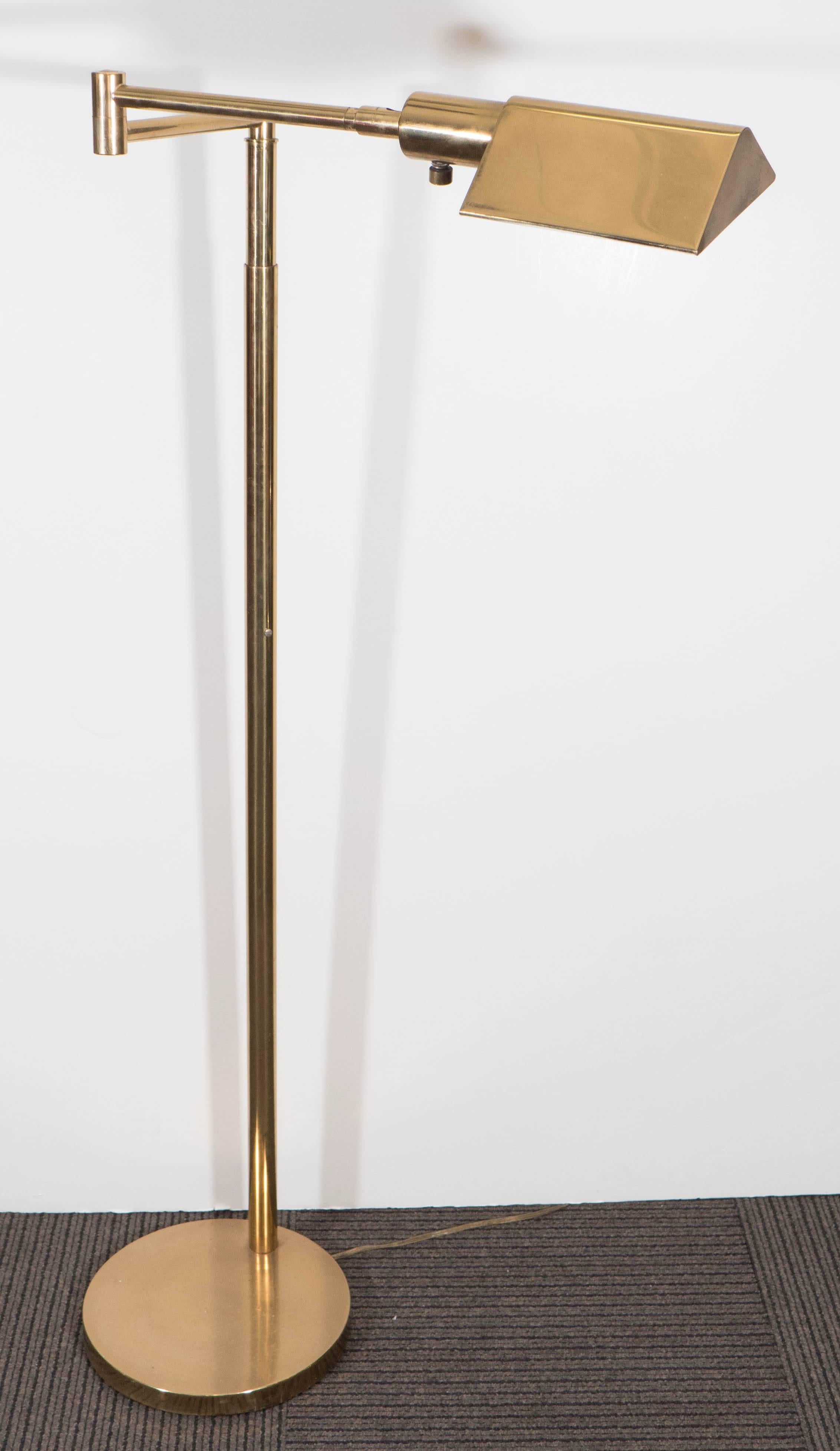 This vintage brass floor lamp, produced circa 1970s by Koch & Lowy, comes with and articulated swinging arm with lengthy triangular shade, as reading light, on lengthy stem and circular base. Requires a single tubular light bulb. The lamp is in very