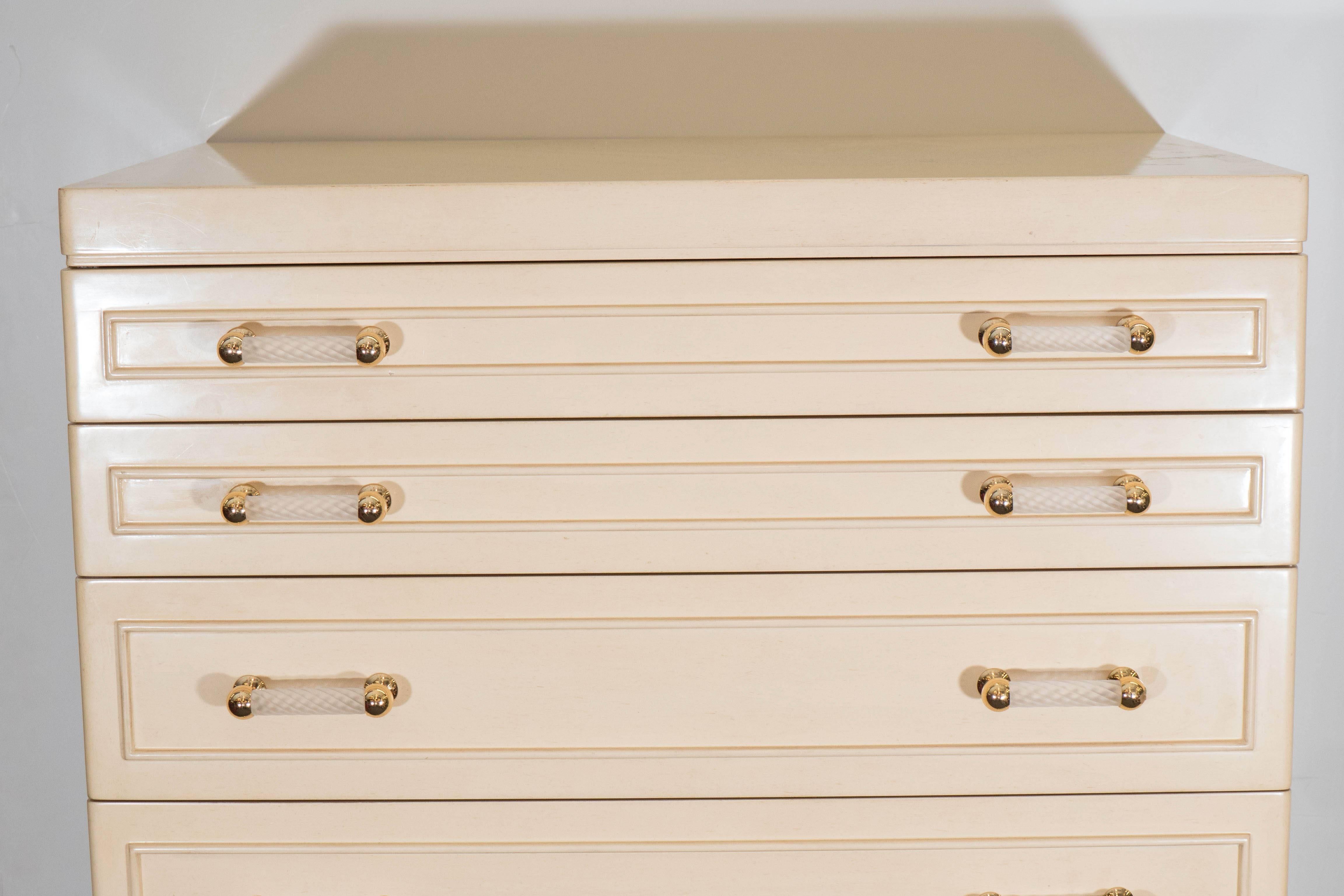 A tall chest of drawers, designed in the elegant Hollywood Regency style, in bleached and lacquered wood, with nine drawers, each including two twisted pull handles in frosted glass and brass. Despite some presence of wear to the original lining in