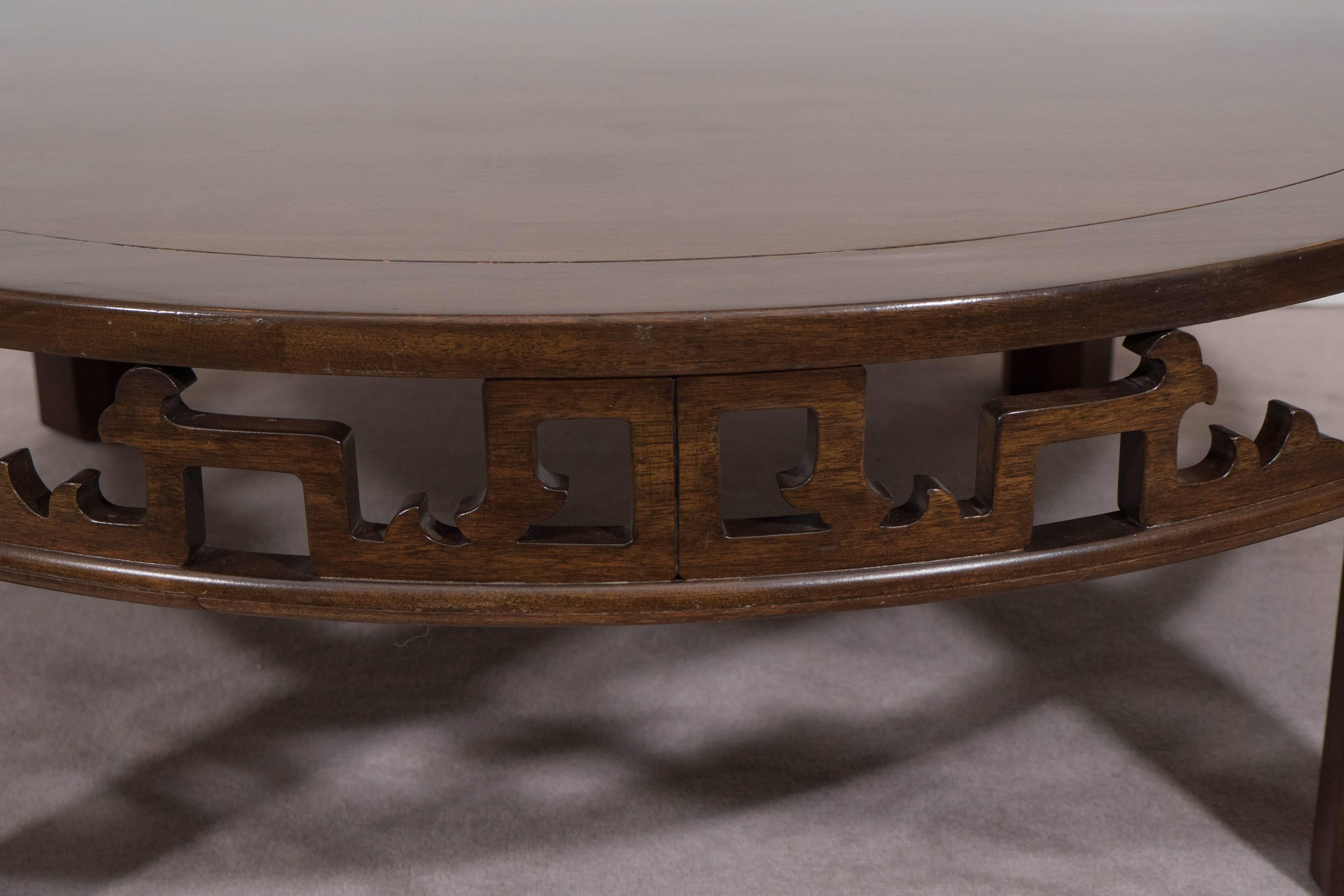 A round 1960s wood coffee table by Baker Furniture, with elaborate open fretwork apron. Markings include [Baker Furniture] plaque to the underside of the table. Despite some surface scratches and age appropriate wear to the table, it remains in very