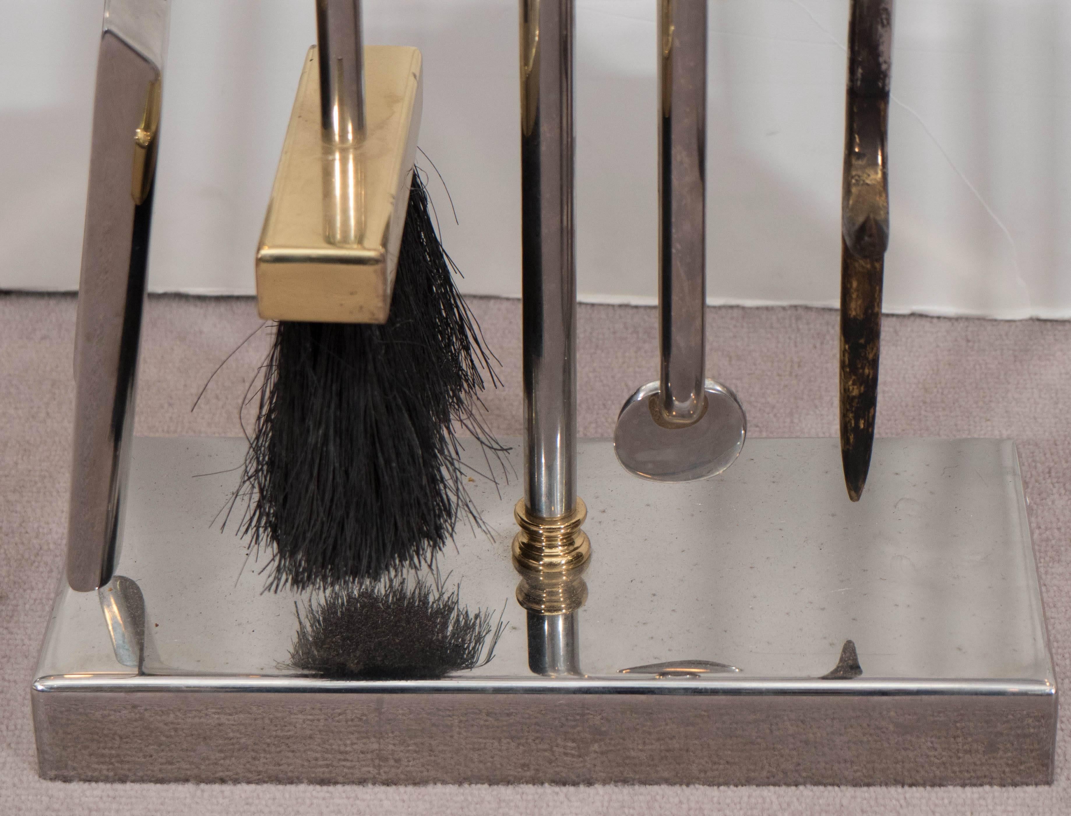 A set of modernistic fireplace tools on stand, designed by Danny Alessandro circa 1980s, including shovel, fire iron, broom and tongs, each in nickel and accented in brass, with ring form handles. Despite some presence of wear to metal finish and