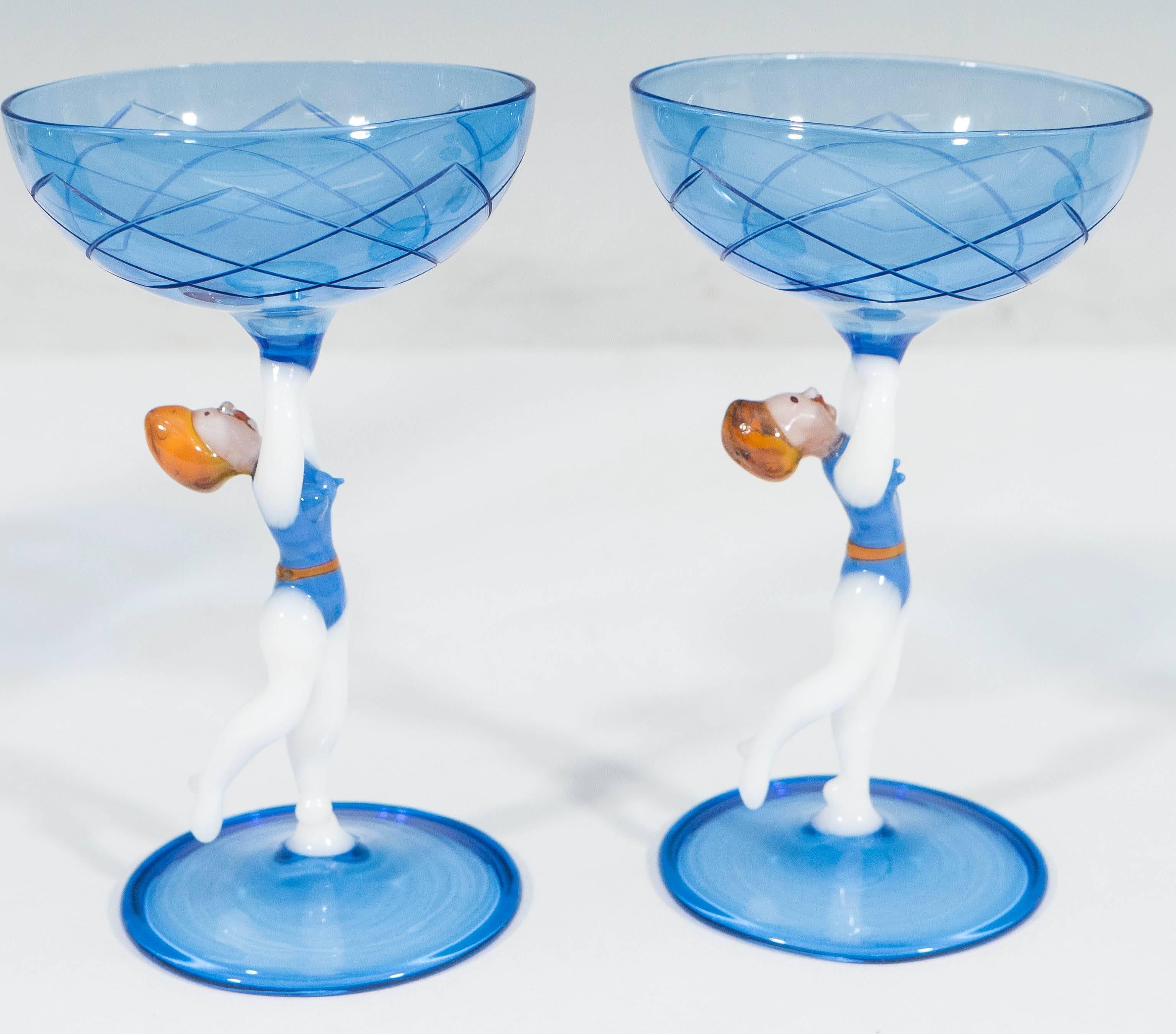 A decanter and matching set of three cordials in hand-blown blue glass, in the style of Bimini, exteriors detailed with crosshatching, the stems designed as synchronized swimmers, with a bikini-clad figure inside the decanter. Very good vintage