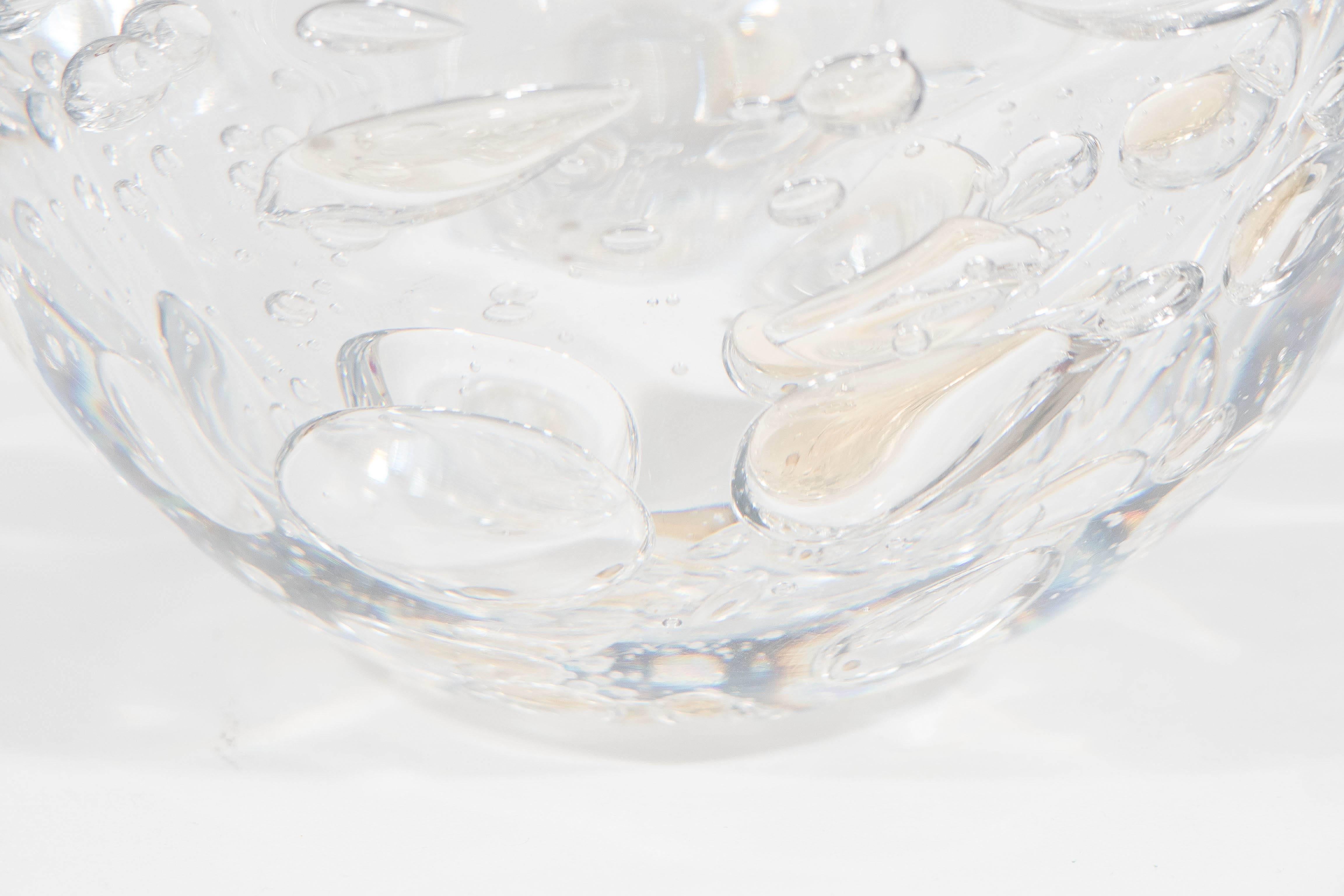 A Swedish decorative bowl in wonderfully heavy clear blown glass, with an array of controlled bubbles, a few in tones of amber, produced circa 1960s by Kosta. Markings include [Kosta Unik] etched to the base. The glass remains in very good vintage