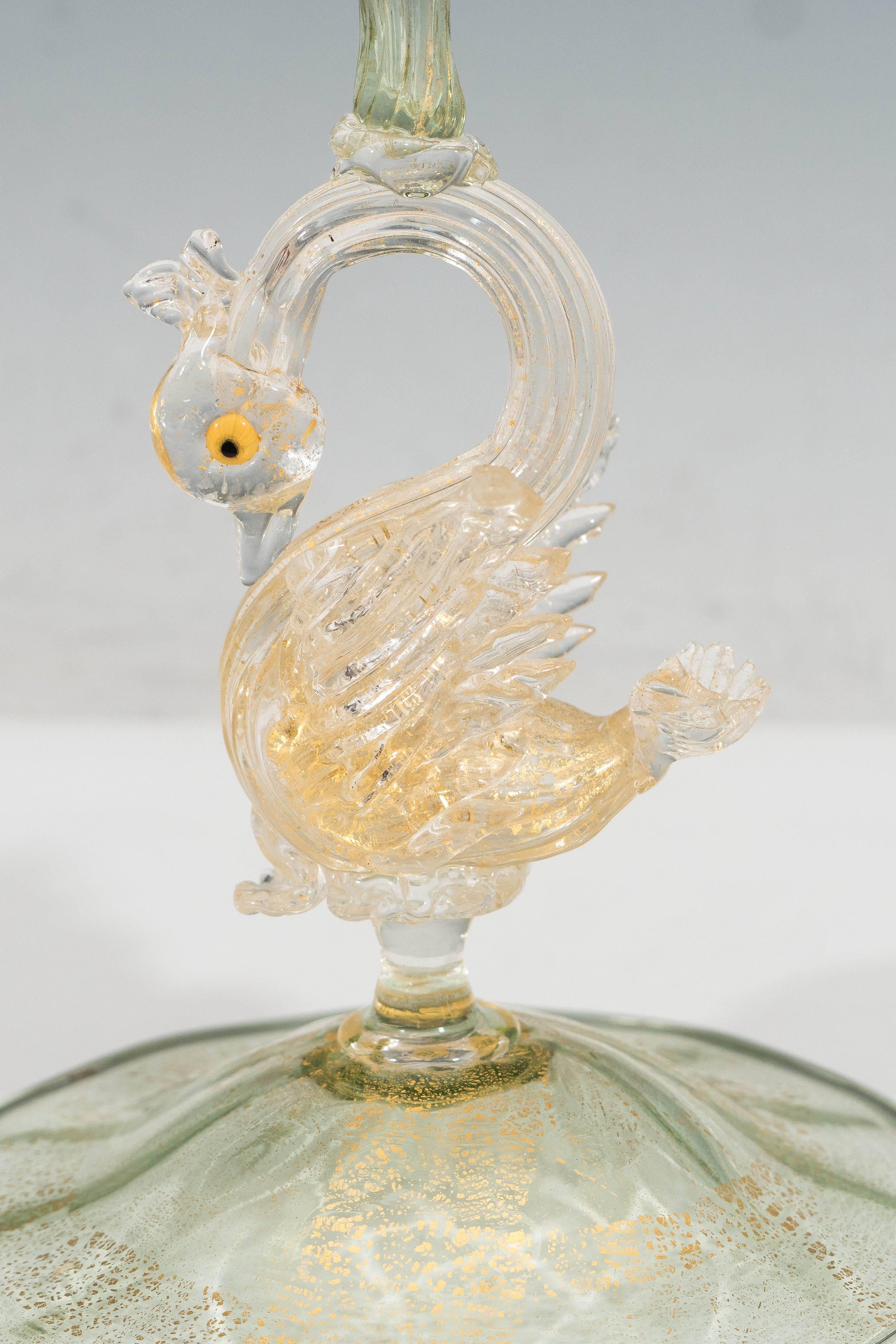 A Venetian handblown glass candlestick, produced circa 1920s by Salviati, light green in tone, with bulb capital and bobeche, over baluster form stem and swan motif on round foot, infused with flecks of gold leaf. The glass remains in very good