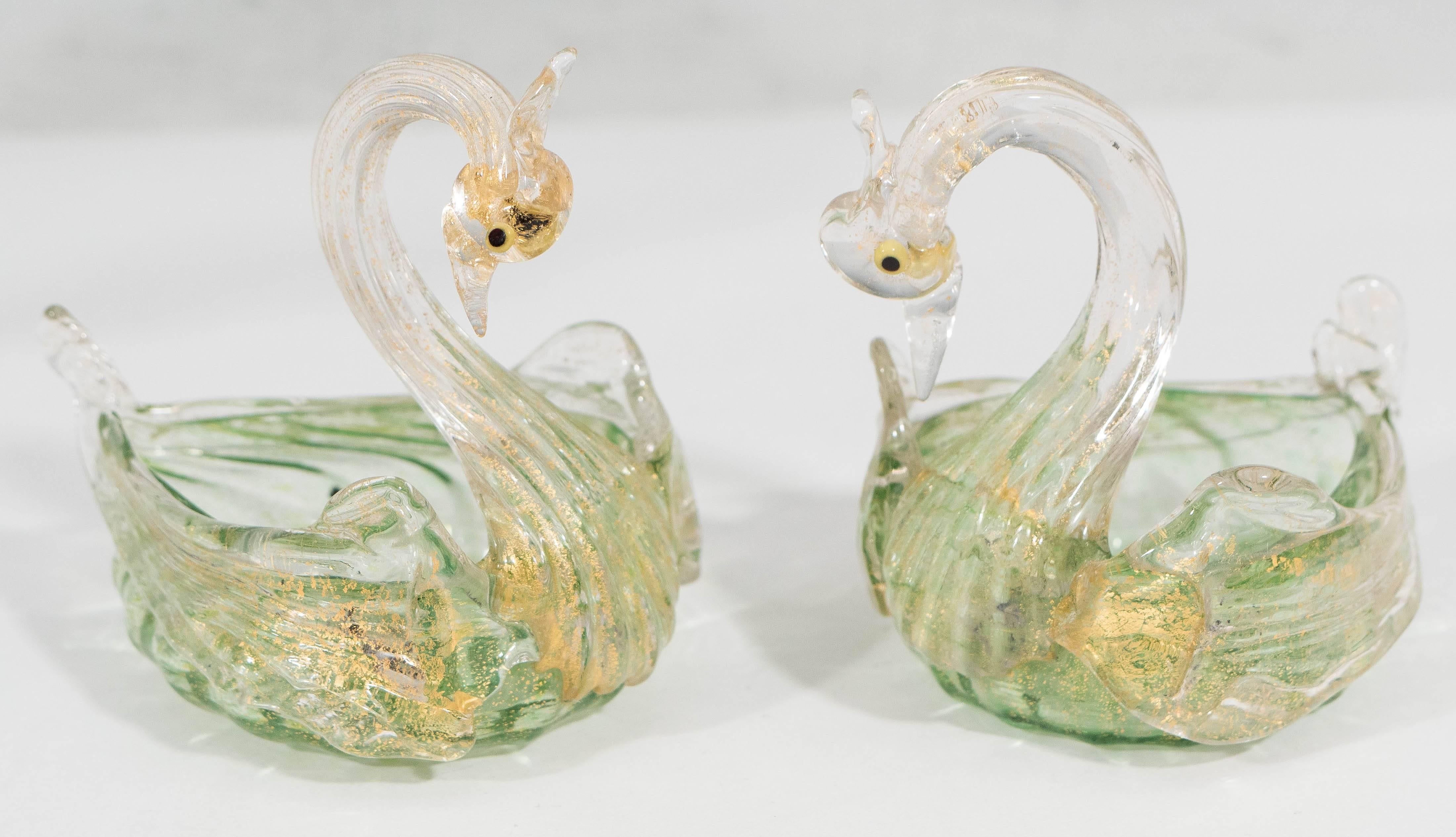 An fine arrangement of Salviati blown glass pieces, in varied tones of green and infused with gold flecks, including a raised bowl featuring a swan as stem, with ruffled swirled rim and round base, and a pair of matching, swan form salt cellar