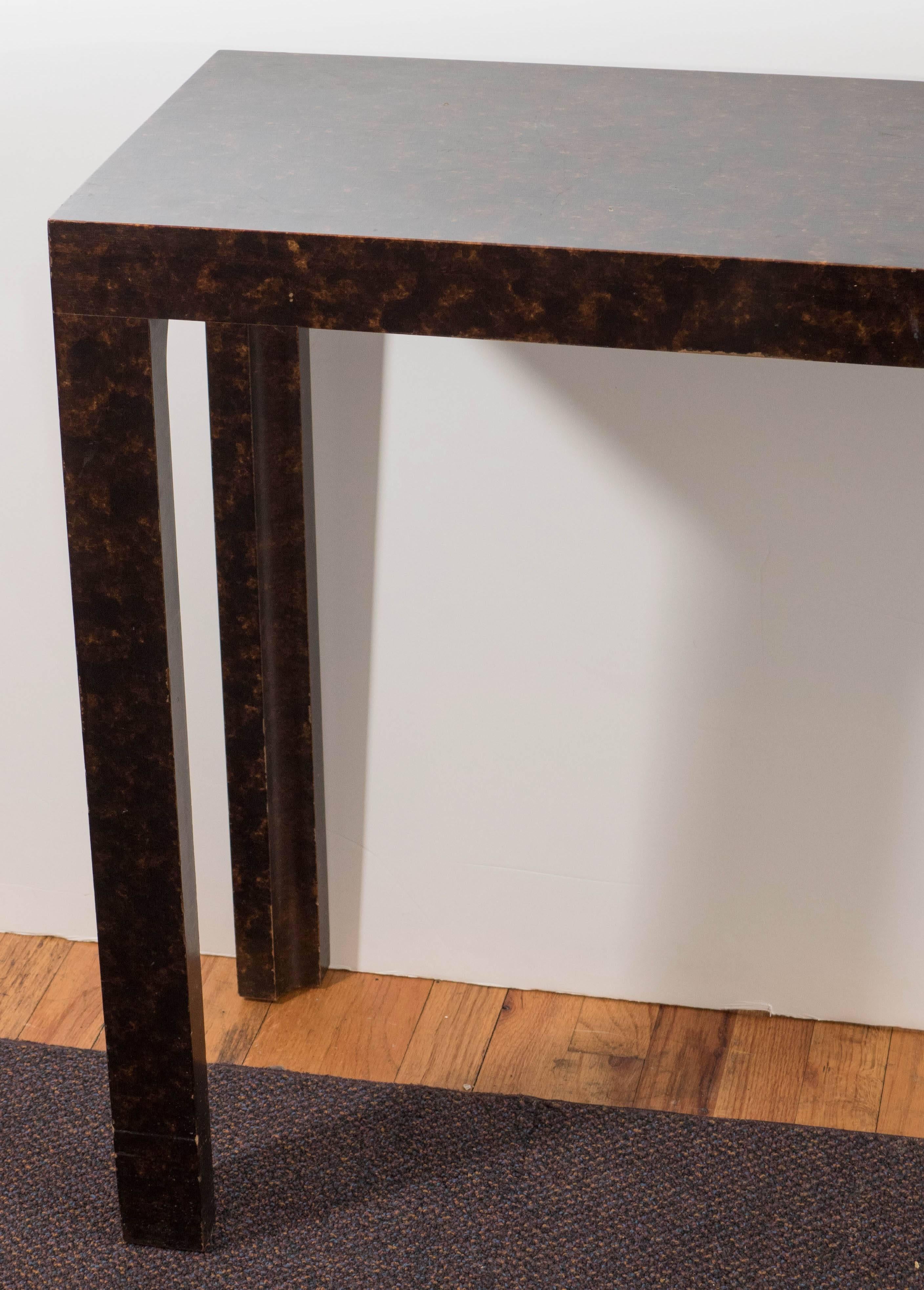 A Parsons style wooden console table by John Widdicomb, produced circa 1960s, covered in faux tortoiseshell. Markings include designer label [John Widdicomb/Makers of Fine Furniture/ Grand Rapids] to the underside of the table. This piece remains in
