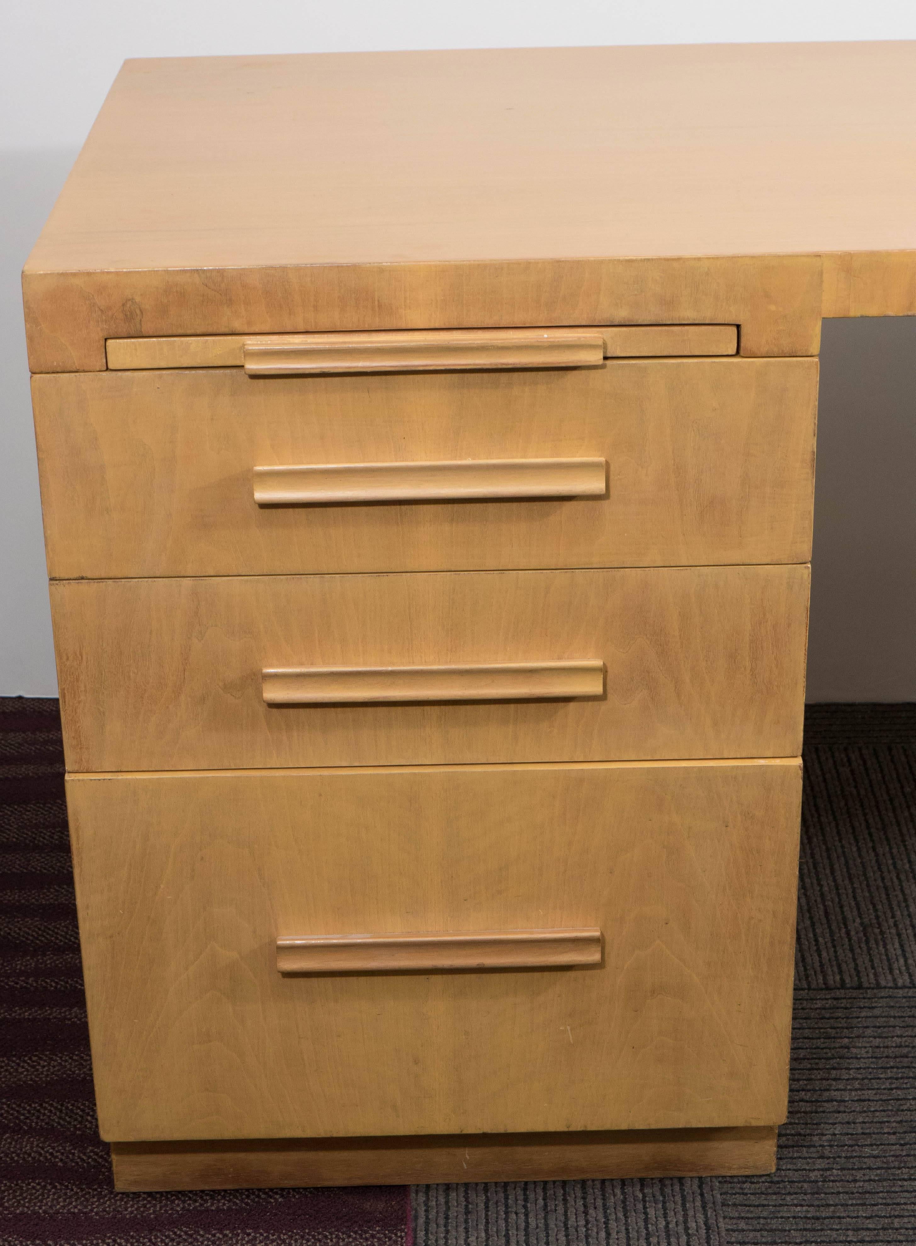 This wonderfully modern executive desk by designer T.H. Robsjohn-Gibbings for Widdicomb, comes in vibrant birch, with three graduated drawers and pull-out writing surface, supporting a curved streamlined top on opposite single tapered leg. Markings