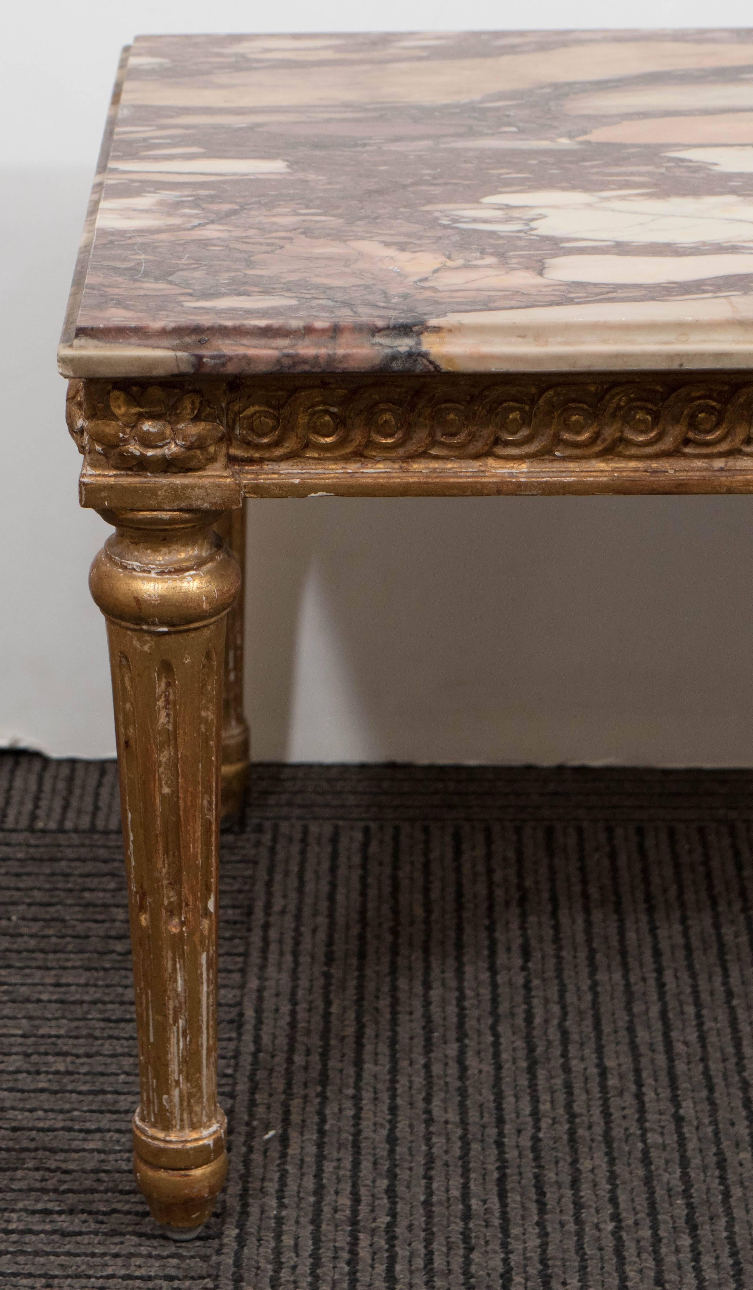 A pair of early 20th century side tables, in the neoclassical Louis XVI style, each with polished Breche d'Alep marble tops over carved giltwood base, with guilloche pattern frieze and rosette corners, on fluted tapered legs. Despite presence of age