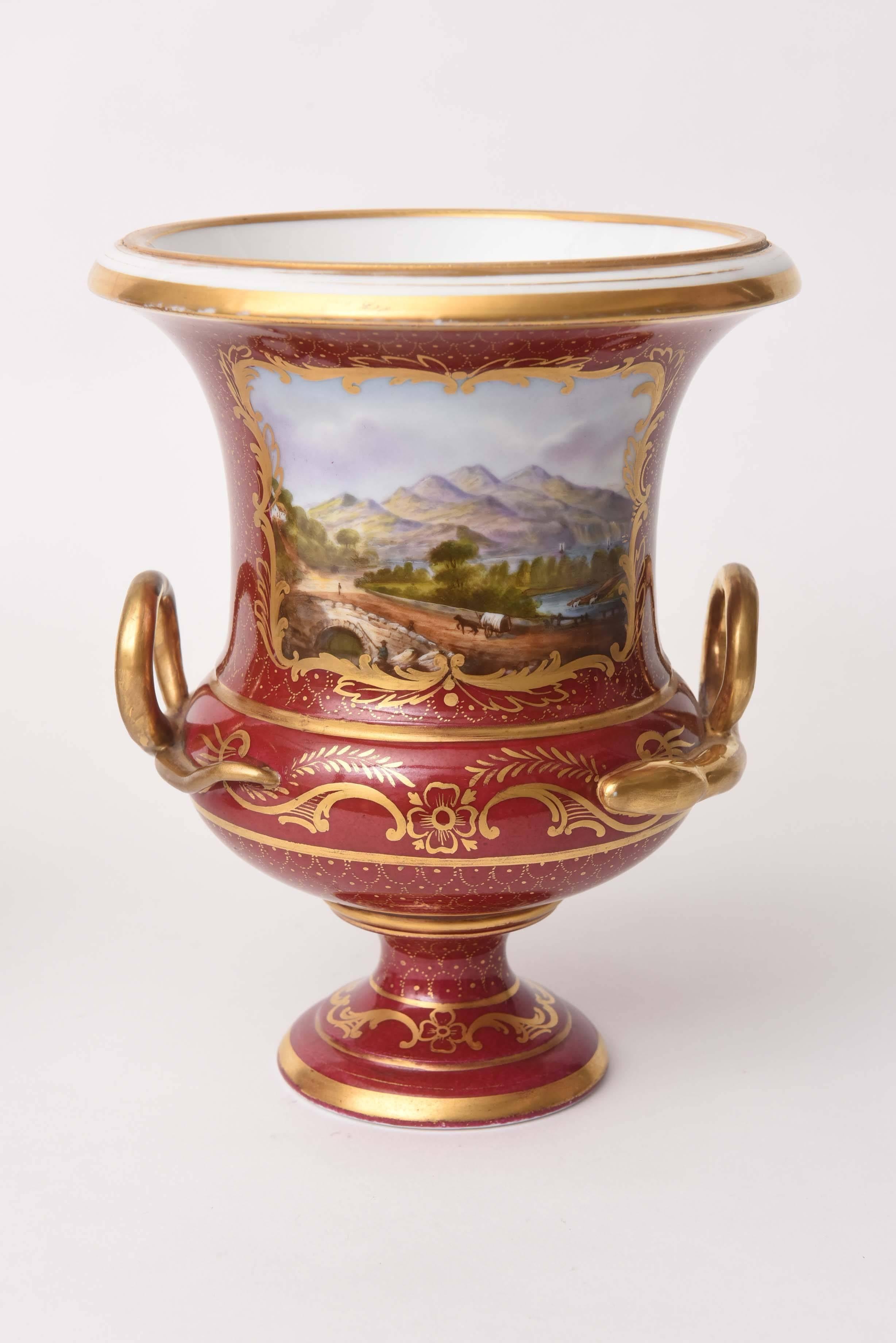 From Royal Crown Derby, one of our favorite English porcelain firms we have this impressive set of two matched urn vases on a nicely shaped pedestal base. Beautiful gilded loop handles and an all-over gilt foliate decoration on a ruby or claret
