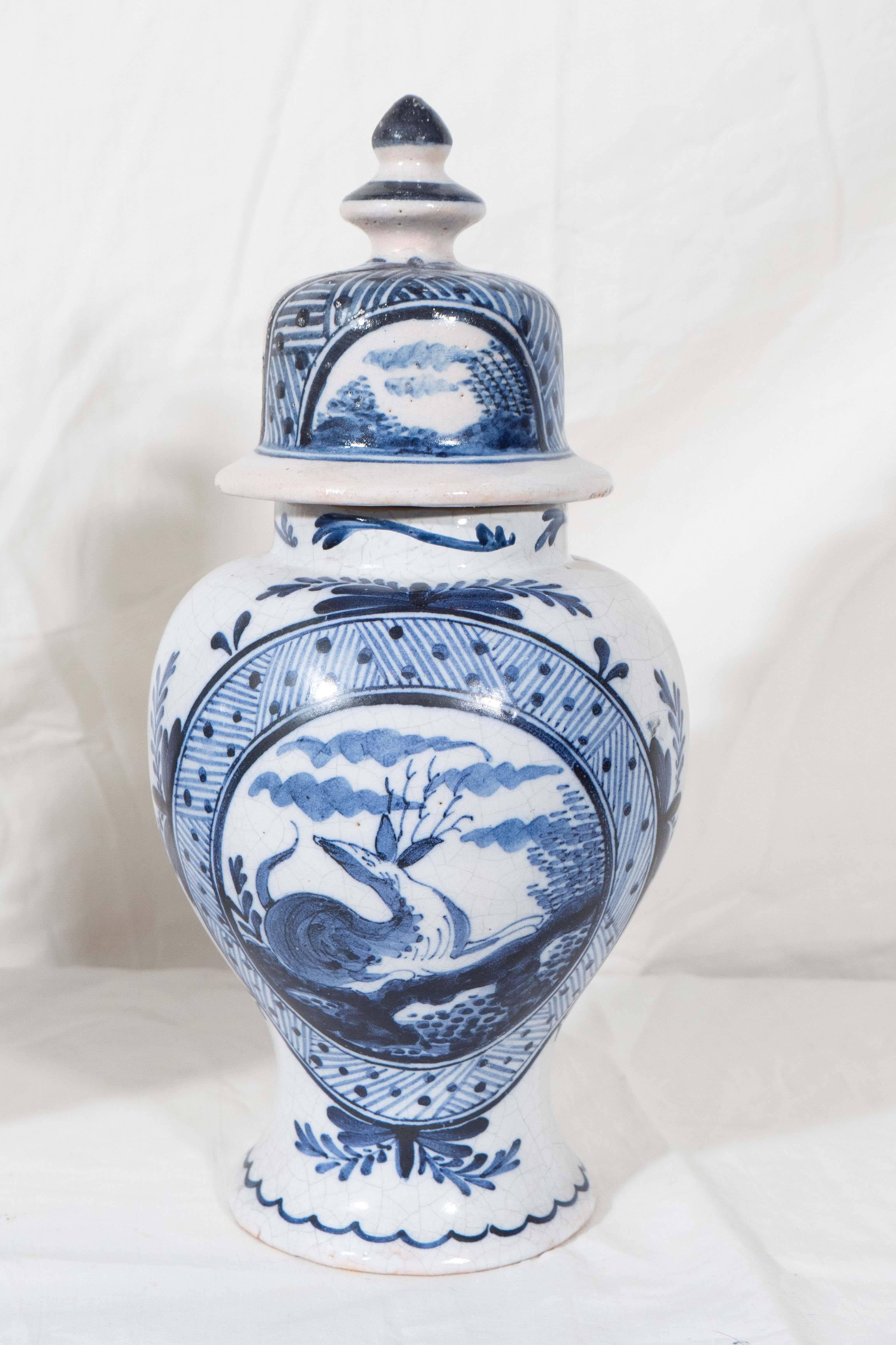 A pair of blue and white Dutch Delft covered vases decorated in cobalt blue showing a single deer resting at the edge of the woods. The scene is enhanced by an interesting border with a lively design of dots and cross hatching. Made in the late 19th