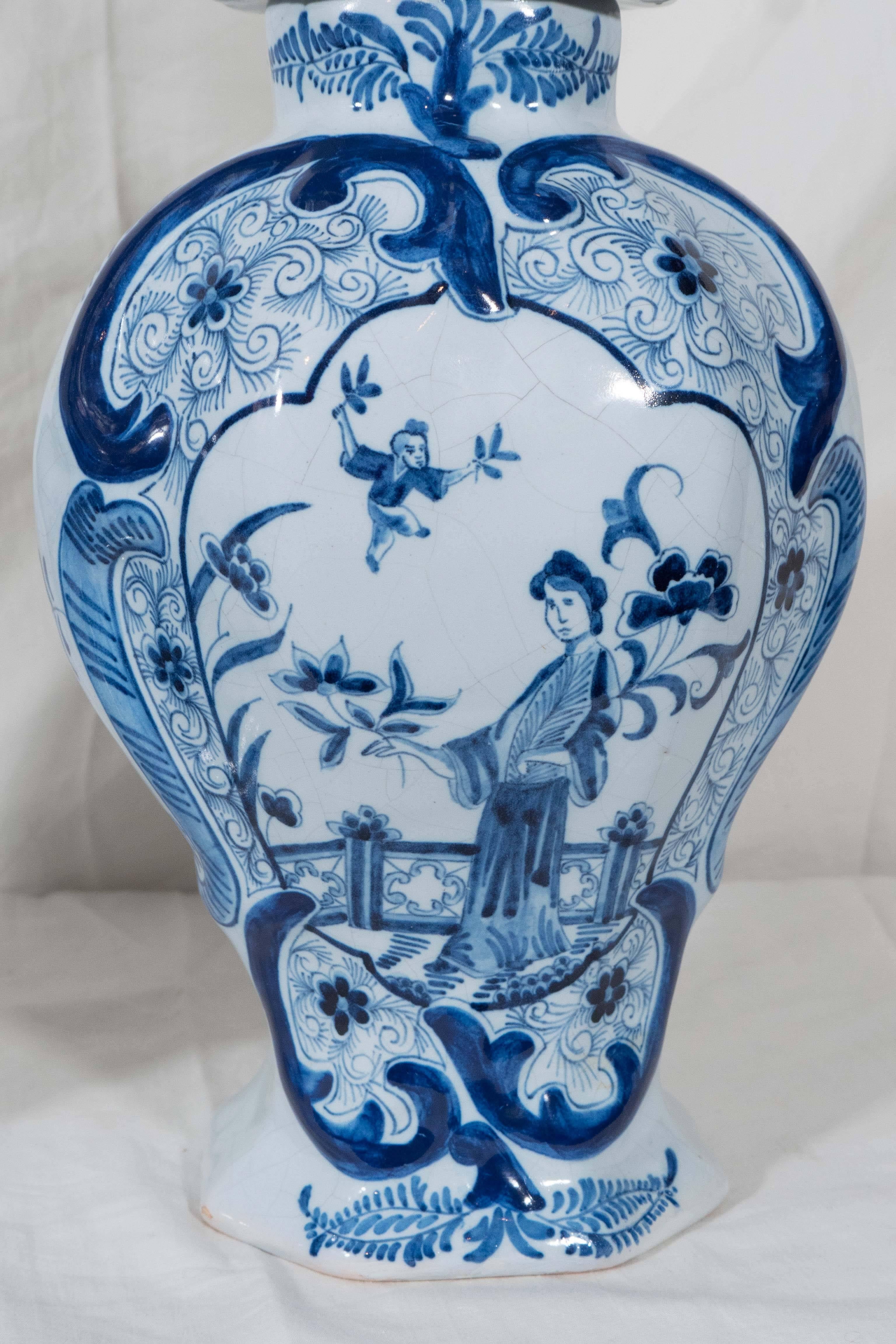A pair of Dutch delft blue and white covered vases decorated in shades of cobalt blue with a chinoiserie design showing a young woman, a 
