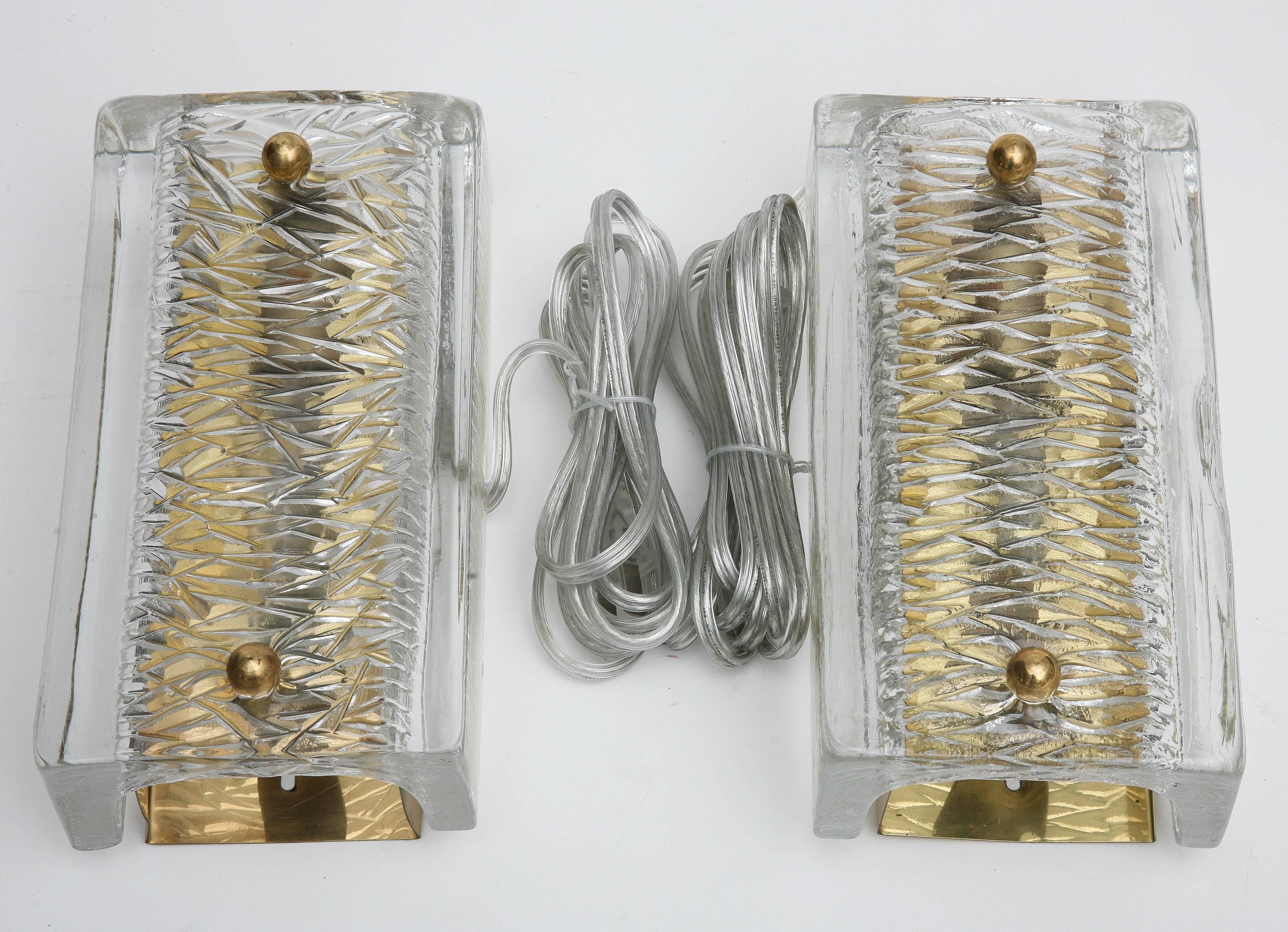 Pair of Orrefors crystal wall sconces by Carl Fagerlund, Swedish, 1960s.
The crystal cover have a linier texture on the inside surface, brass backplate,
with round brass connecters. They have been cleaned and rewired to US standards, each sconce