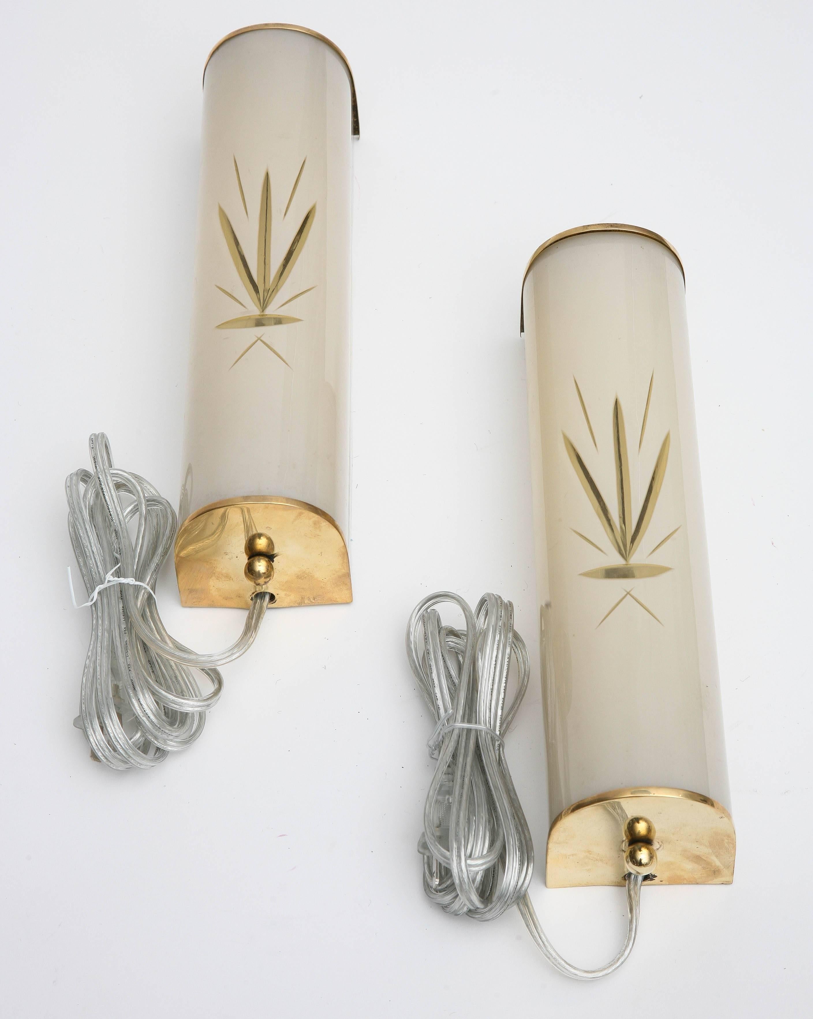 Pair of brass wall sconces with frosted glass and sand etched design in the
glass, off-white color glass, brass top and bottom trim, one candelabra bulb per sconce, 40 watts max
Wired to US standard, 11.50 in H x 3.00 in W x 3.00 in D.