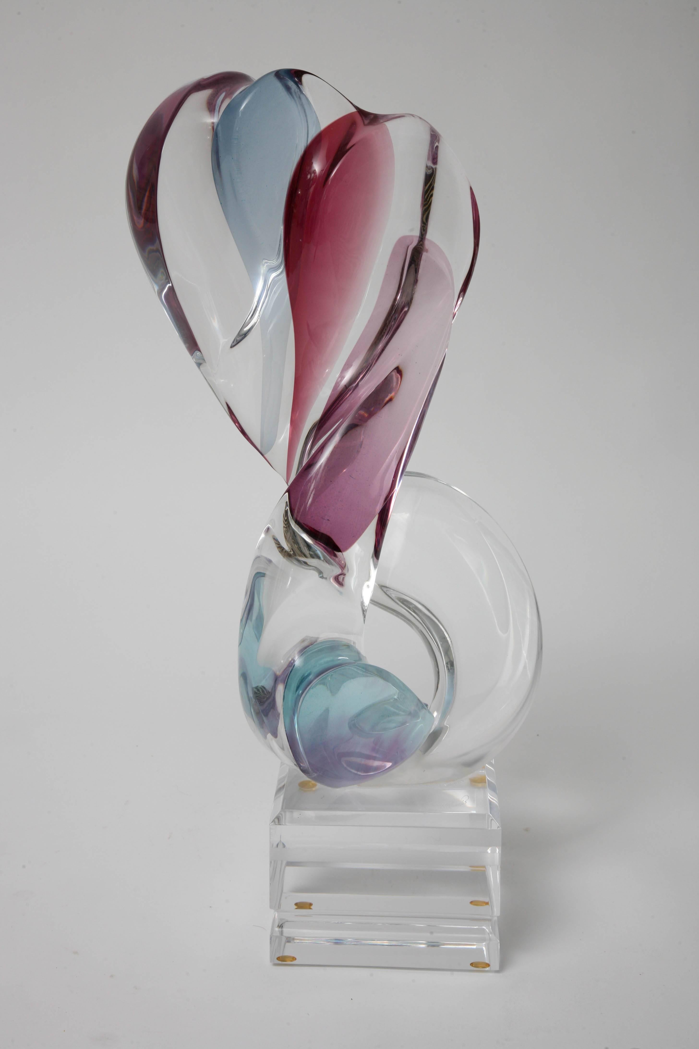 This Lucite sculpture is by the sculptor Michael Bene' and here he it would seem to be that he has captured two lovers embracing. As the two lovers embrace they seem to form the shape of a heart. The artist use of blues for one figure and rose for