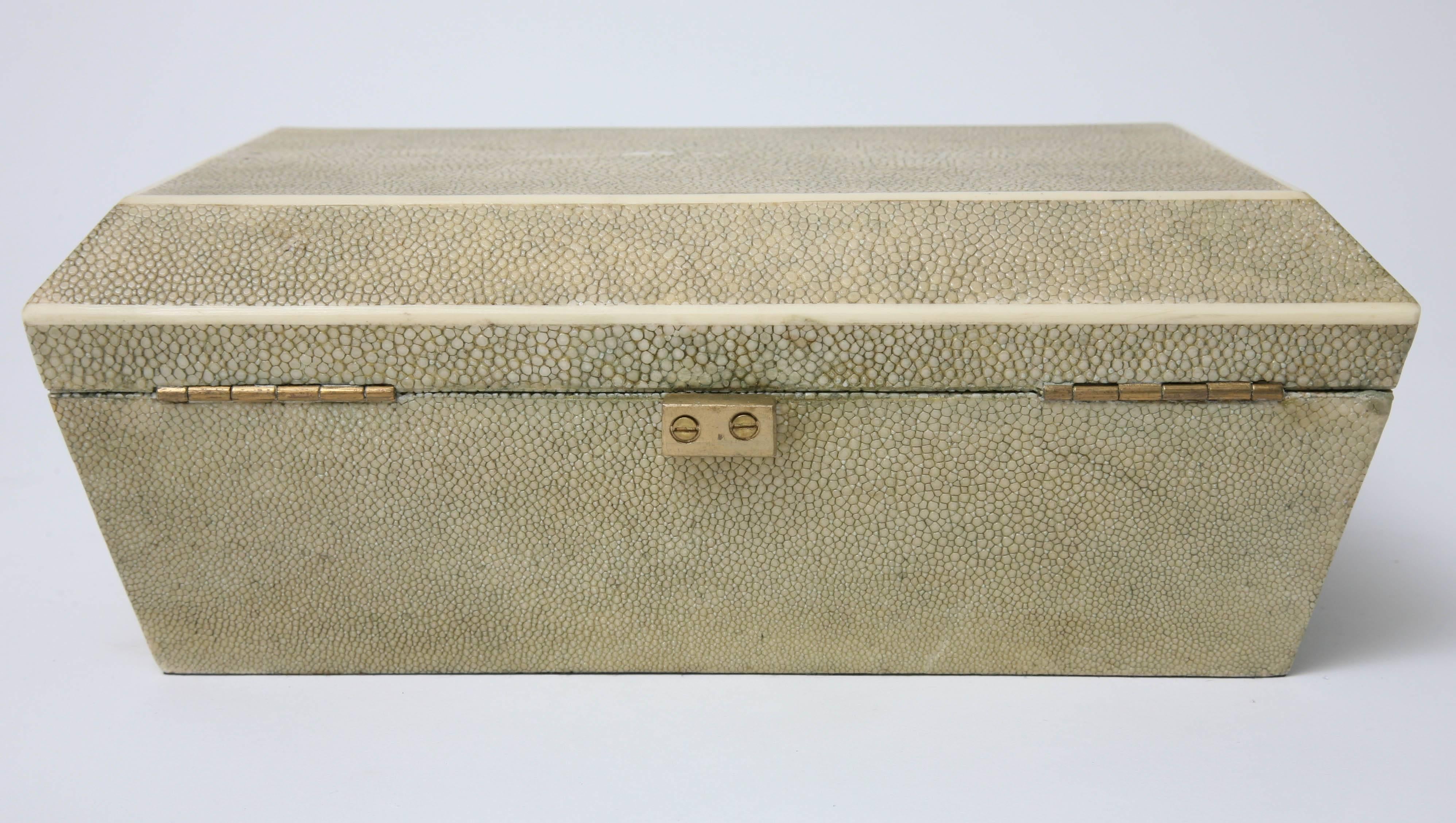 This handsome shagreen and bone box was created by the iconic firm of R & Y of Paris. The shagreen is in a beautiful light-washed-out green coloration with a natural bone-trim and the interior of the box is in a dark-black velour fabric.

For best