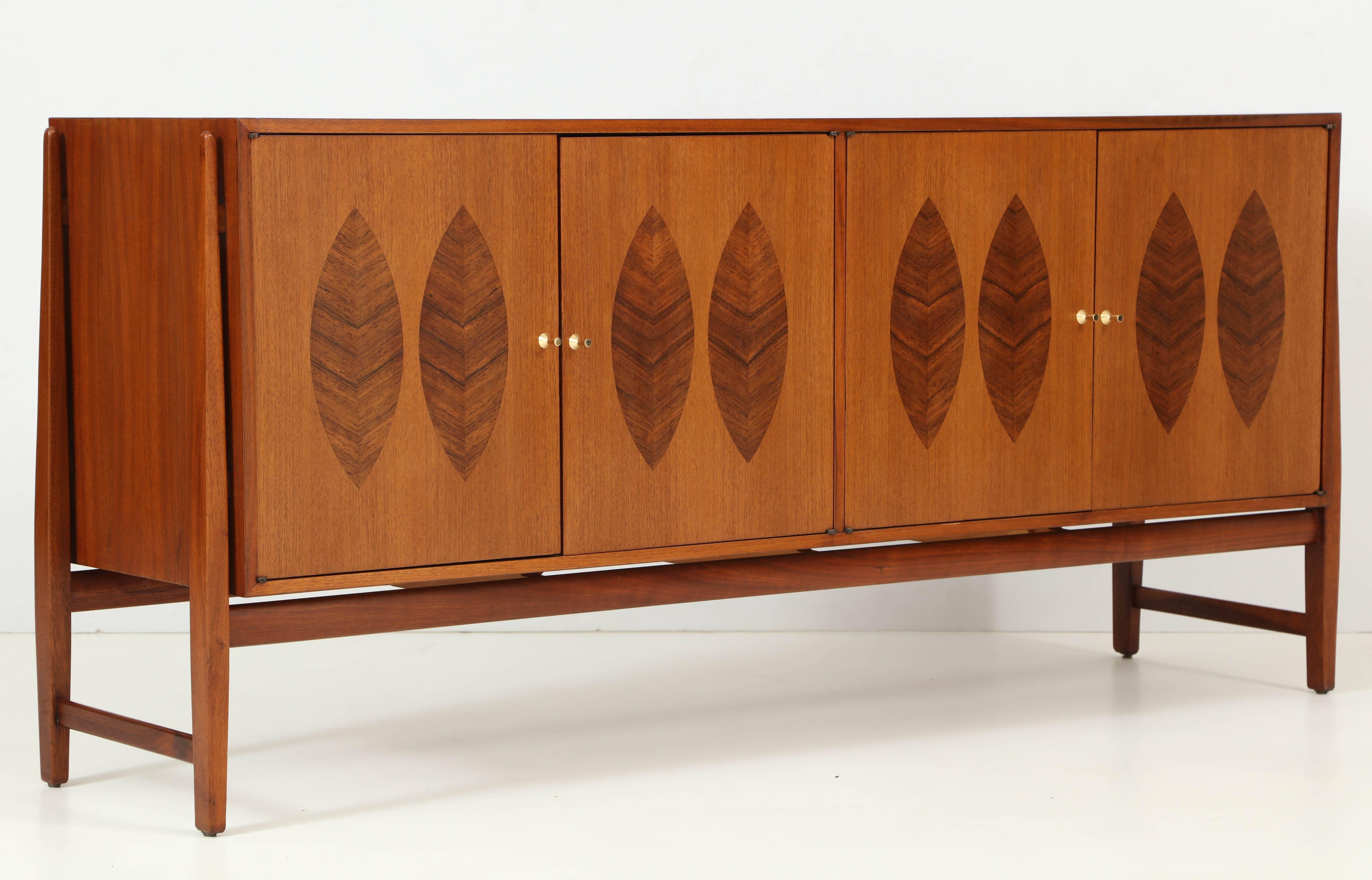 American modernist 1960s teak credenza with inlaid rosewood leaf motif on the doors and polished brass handles, designed by Kipp Stewart. Wonderful Mid-Century Modern aesthetic and exceptional materials and quality. Cabinet features two drawers for