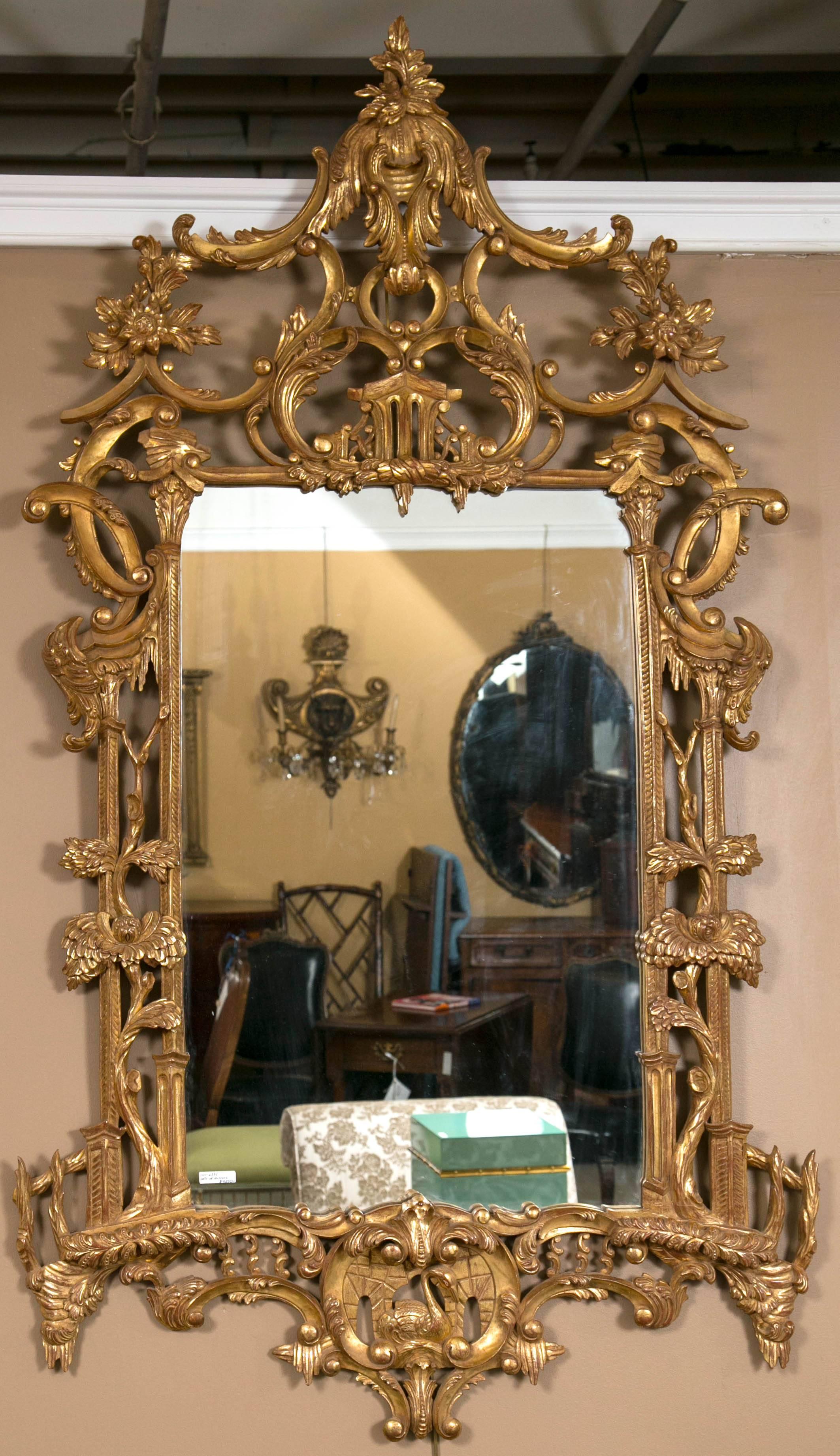 A finely constructed pair of solid wooden Chinese Chippendale style hanging wall / console mirrors. The bottom with a swimming swan on a Lilly Pod flanked by an all around leaf and vine with scroll frame terminating in a pagoda carved pediment top.