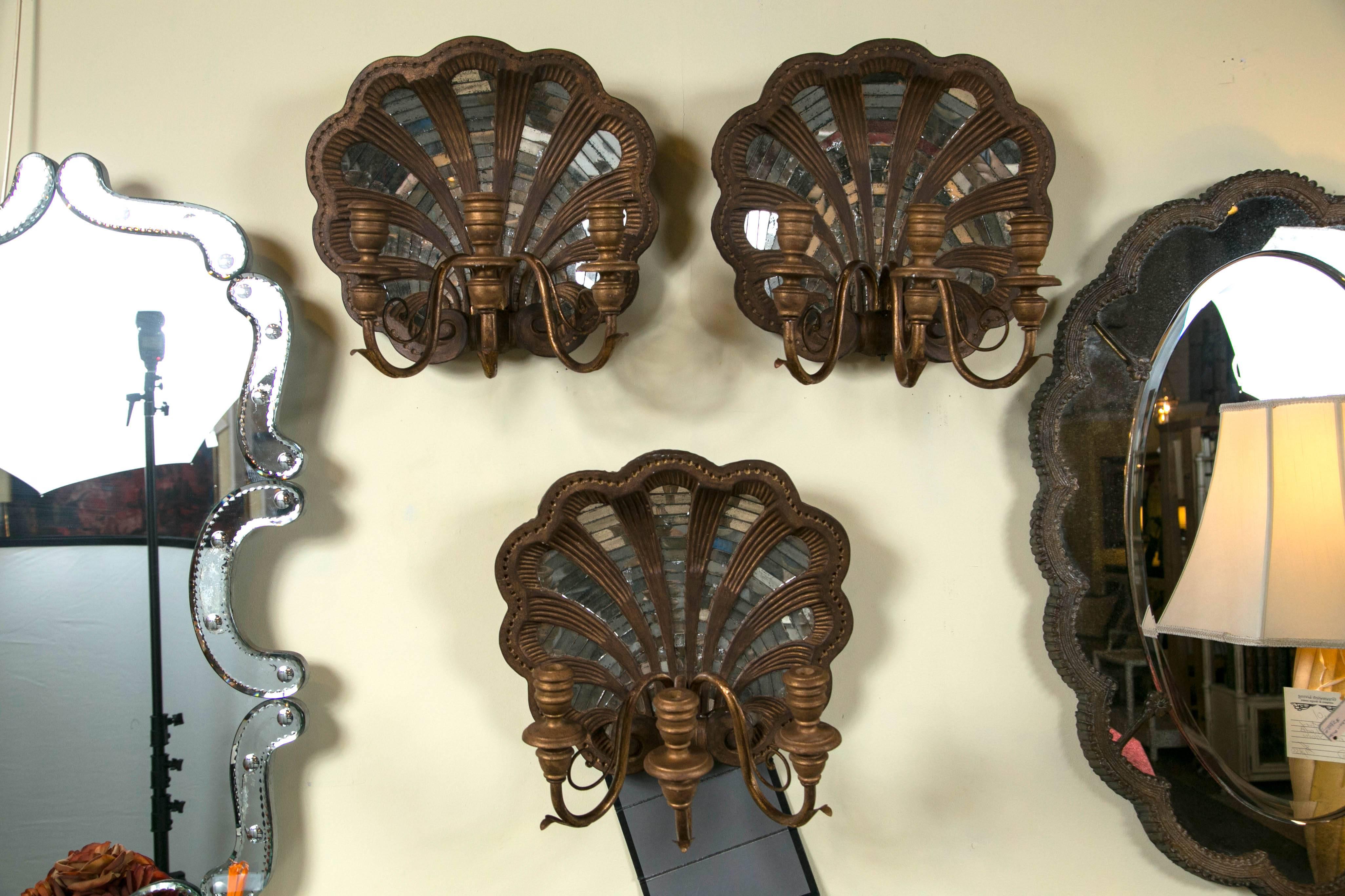 A set of four wooden shell and mirror wall sconces. A fine and rare set hand-carved wooden and mirrored wall sconces. Each having three arms for candle or lighting, wiring would be required, on a shell form of Fine quality design.