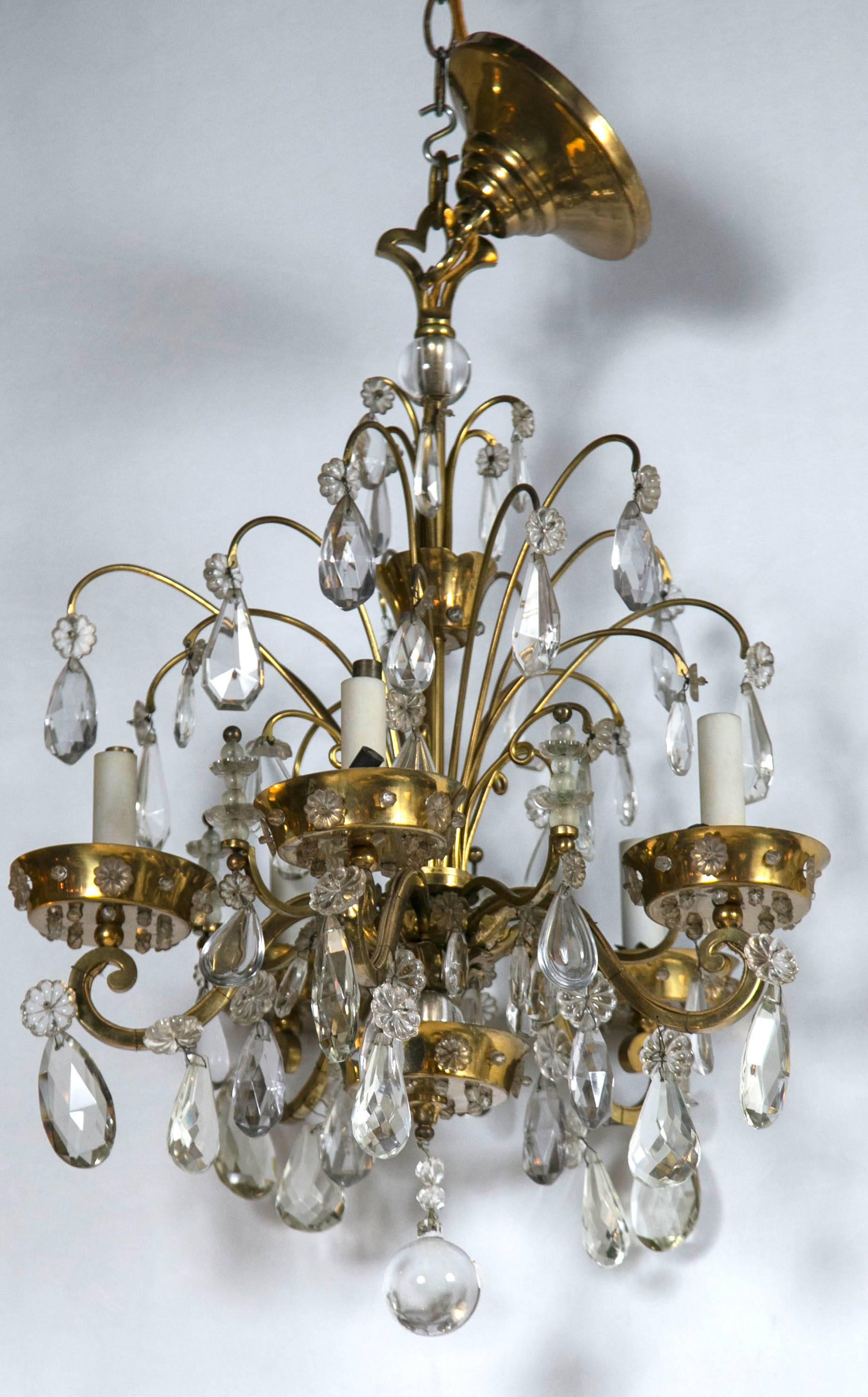 A fine bronze and crystal chandelier by Maison Jansen. The five-arm bronze piece with floral and scroll design having crystals cut into the candle like trays. Recently re-wired and cleaned. This chandelier is sure to not only light up any area its