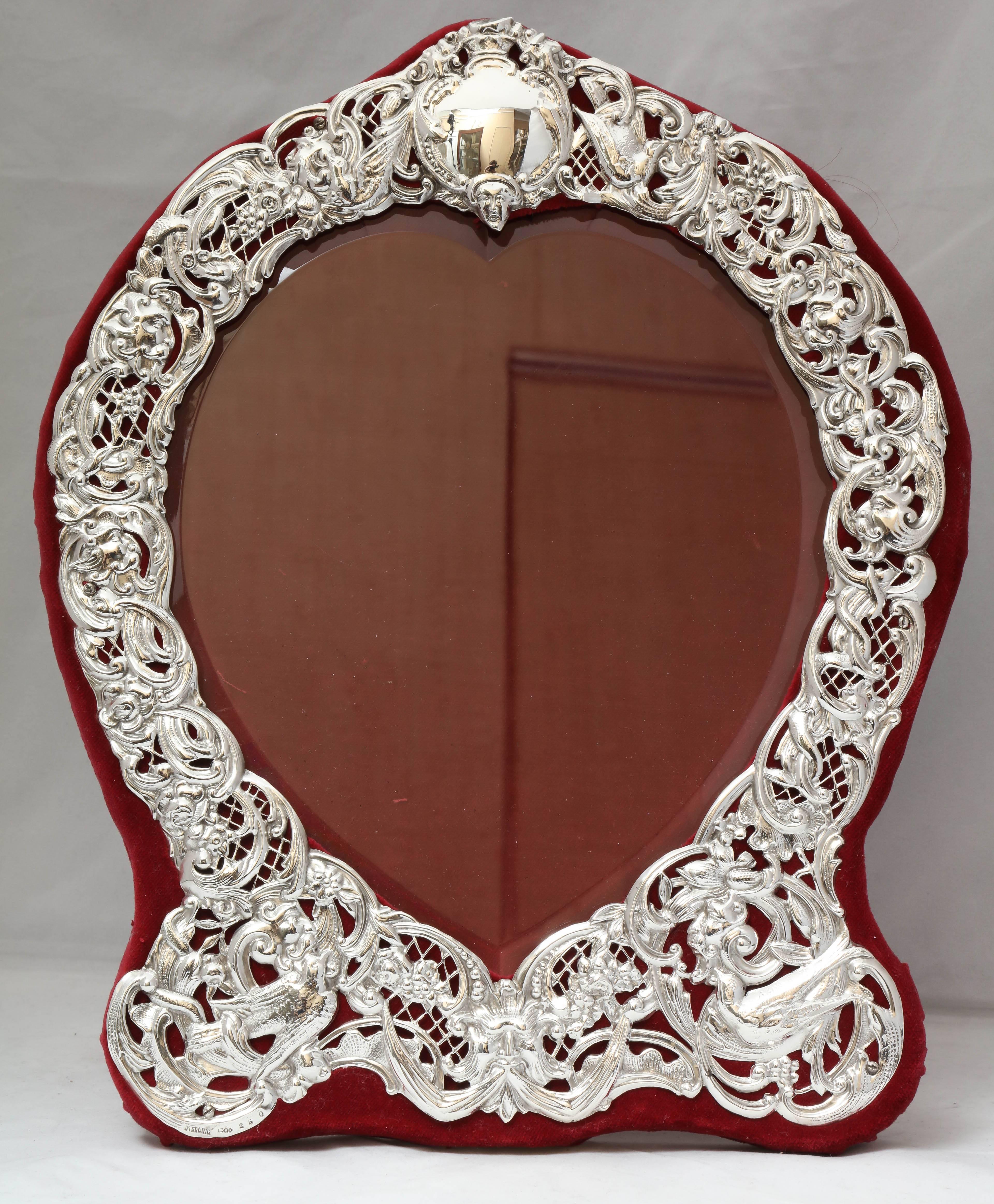 Large, sterling silver, heart-form picture frame, Dominick & Haff, New York, circa 1895. Pierced work allows velvet to show through the design. Edges of heart-shaped glass are beveled. Measures: 14 1/4 inches high x 11 3/4 inches wide (at widest