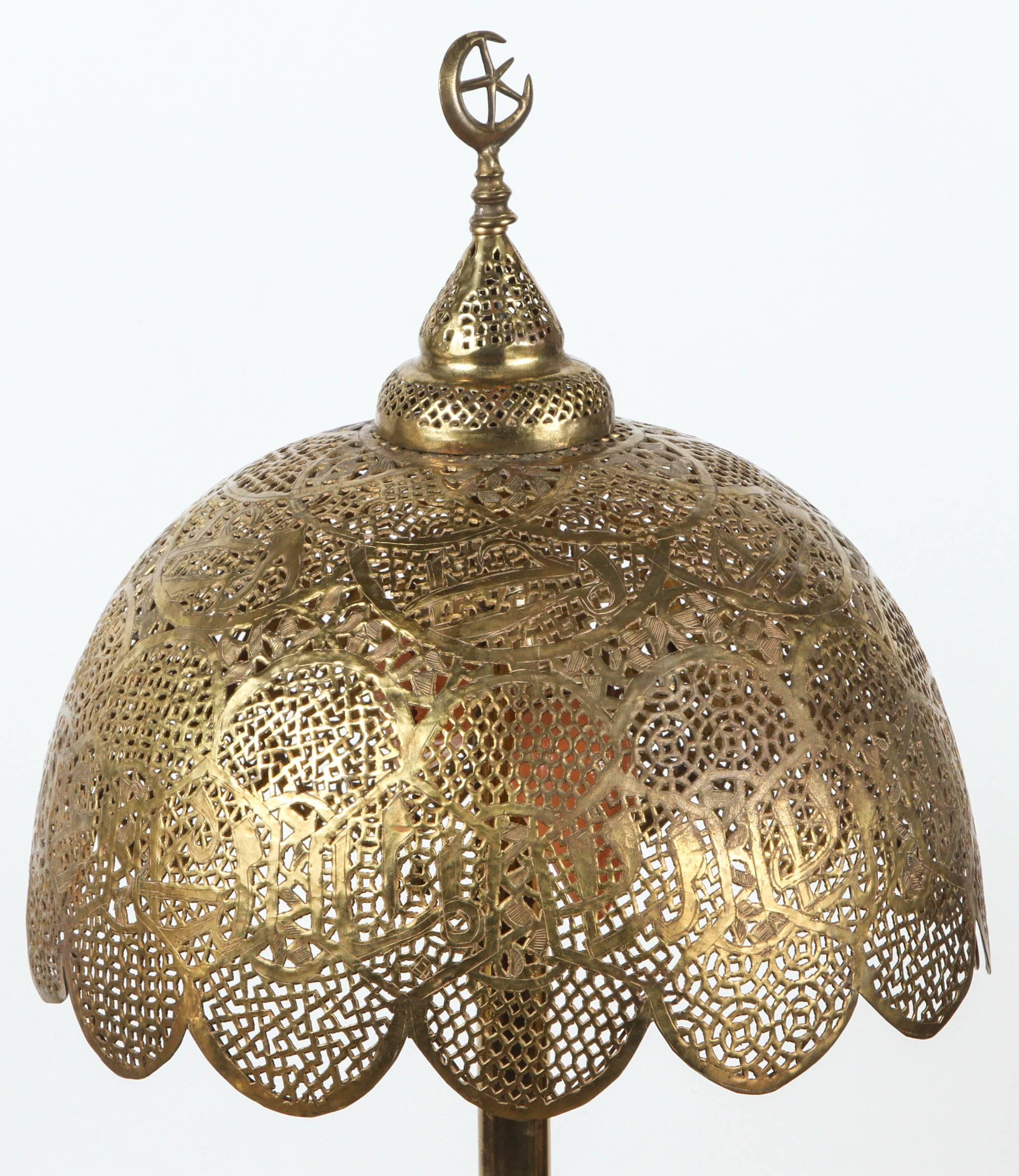 Middle Eastern Syrian Moorish Revival with Arabic calligraphy.
Moorish Revival Syrian brass table lamp with pierced filigree brass stand and shade and surmounted by the moon and star. 
Handcrafted in Syria, there is a light in the bottom and two