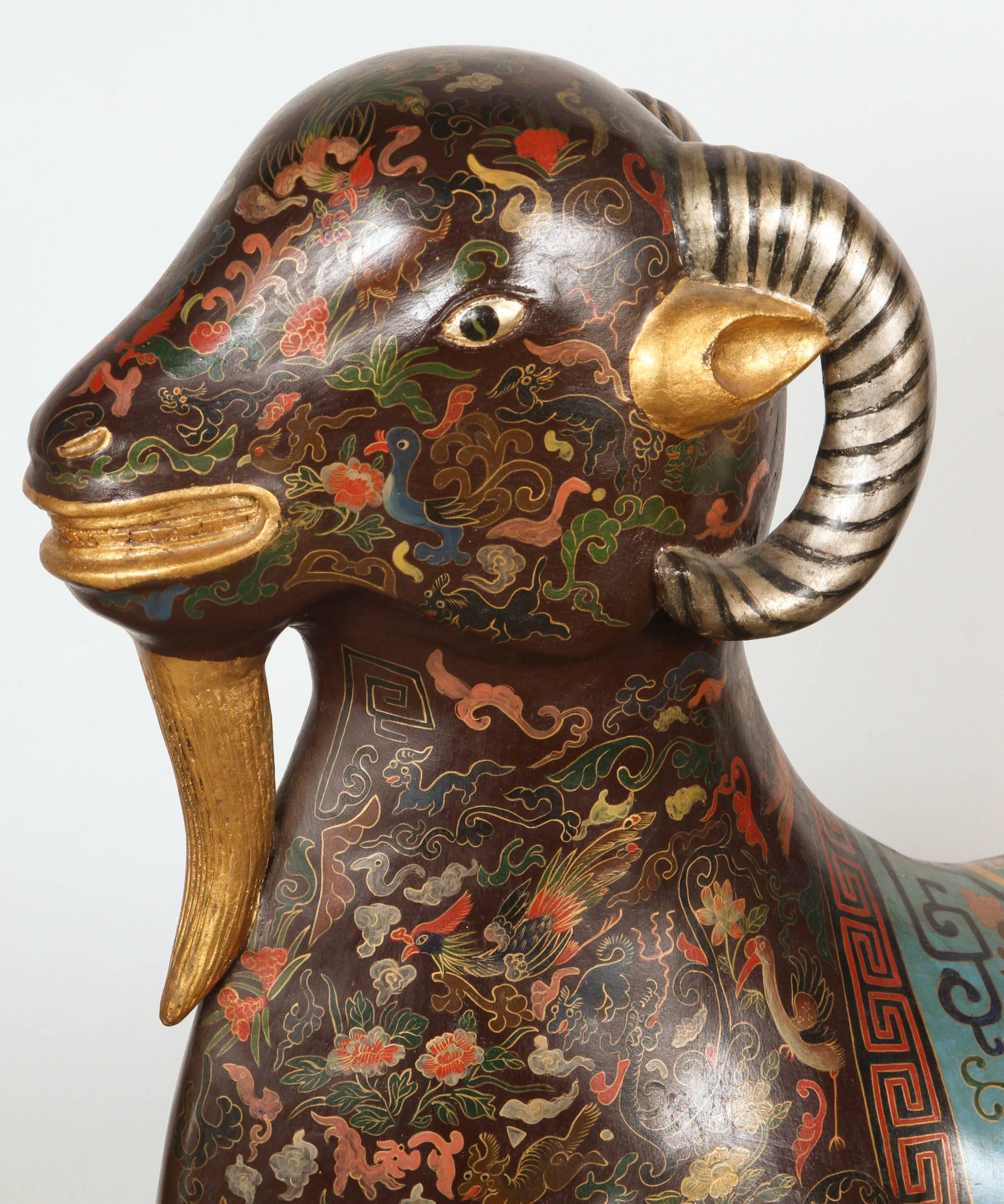 Der asiatische liegende Widder ist auf vergoldeten Hufen ruhend dargestellt, mit erhobenem Kopf und schwarzen Augen, die geradeaus blicken, mit leicht geöffnetem Maul, fein verziert mit einem dichten verschnörkelten Muster aus Golddraht auf braunem