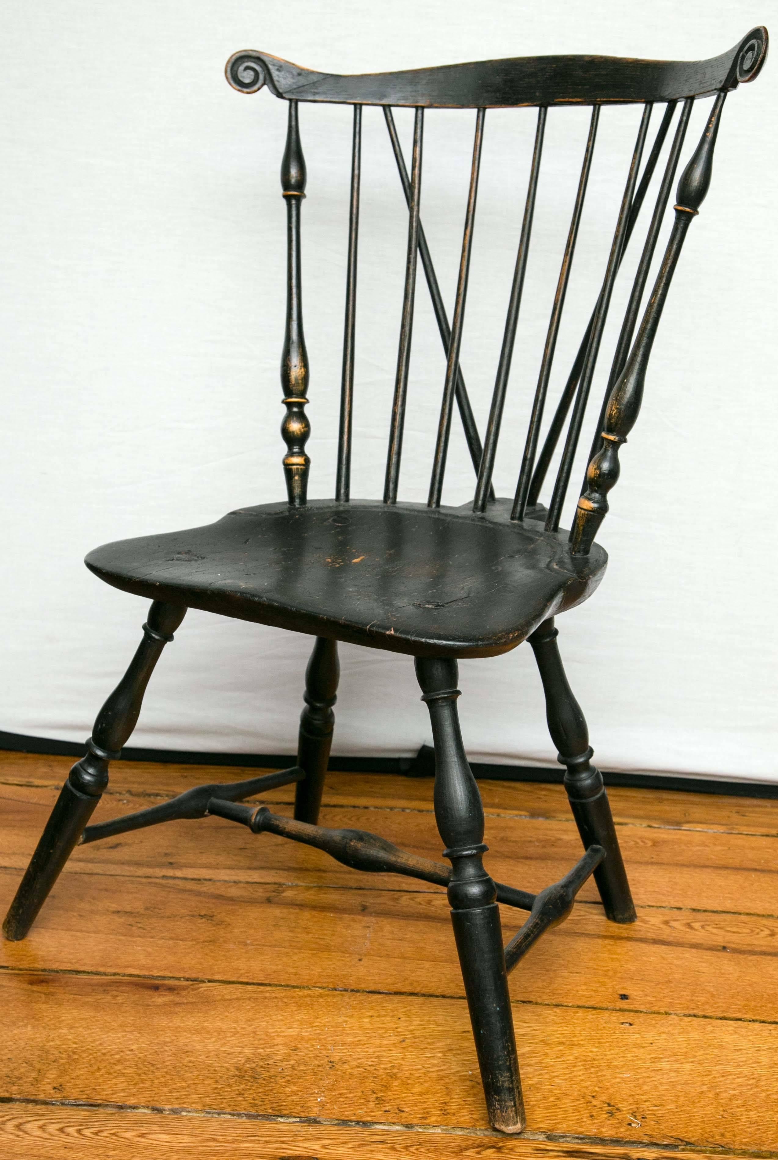 Fan-back brace-back windsor side chair having serpentine crest rail with carved ears and spindle back above a saddle seat on vase-turned legs joined by a recessed stretcher. Old black paint. Wonderful shape and proportions. 

Pennsylvania, circa